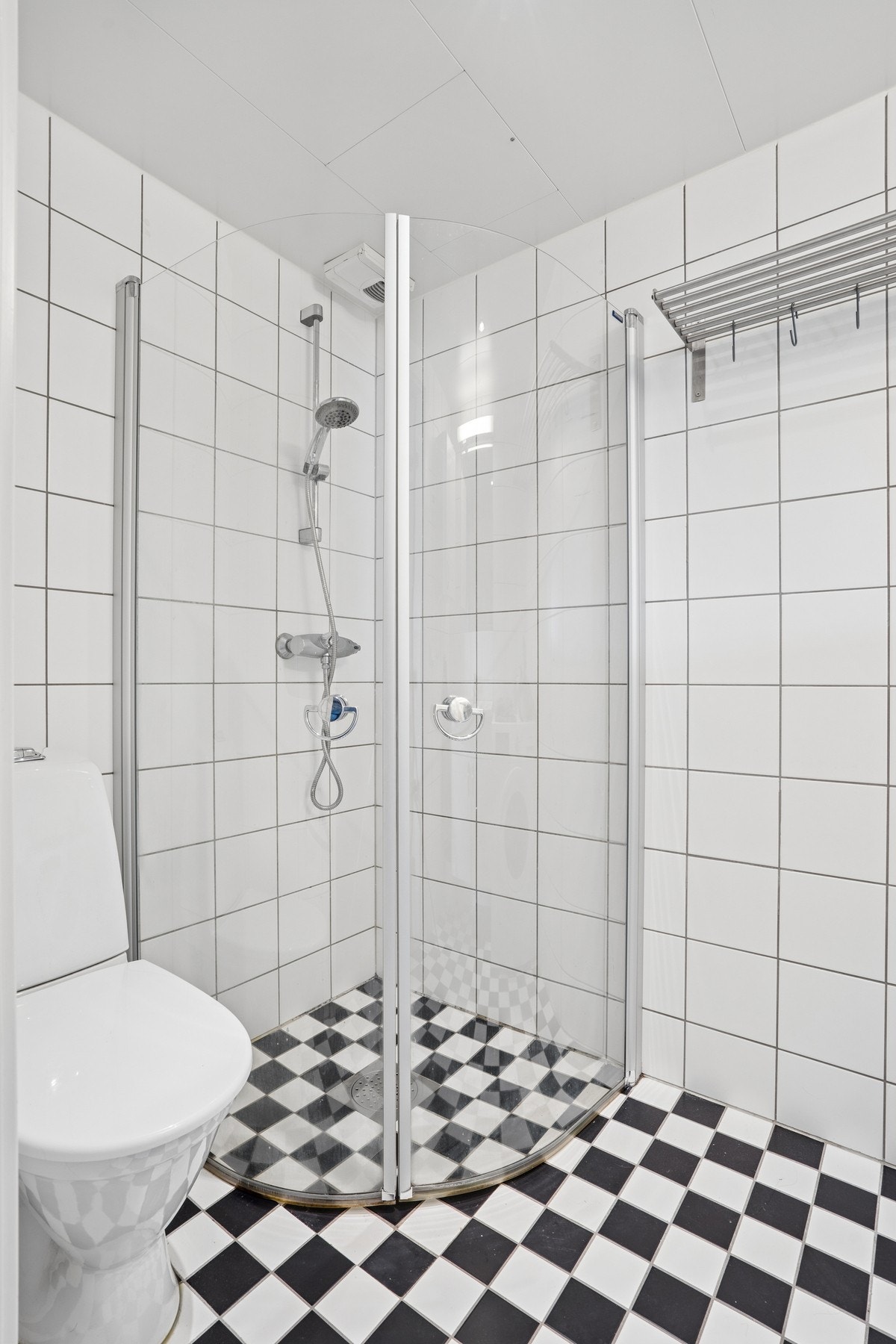 Badet har flislagt gulv med elektriske varmekabler og et dusjhjørne med innfellbare glassdører. Galleribilde