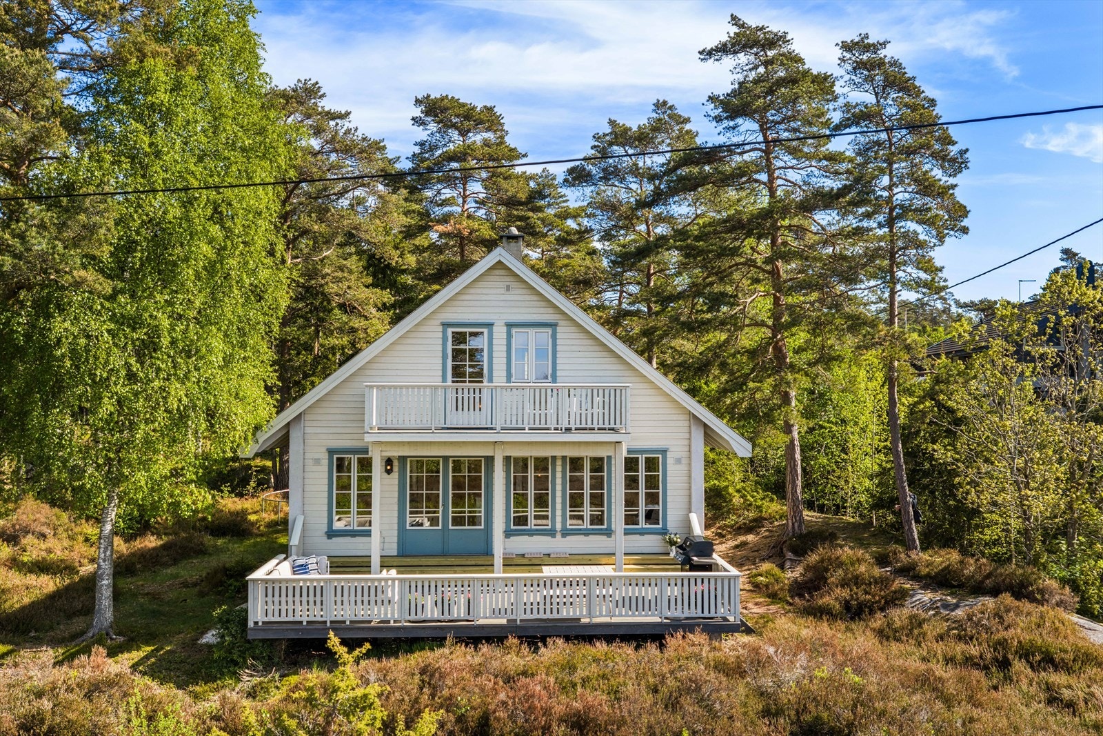Fritidsboligen ligger fint til i terrenget, omgitt av furutrær. Galleribilde