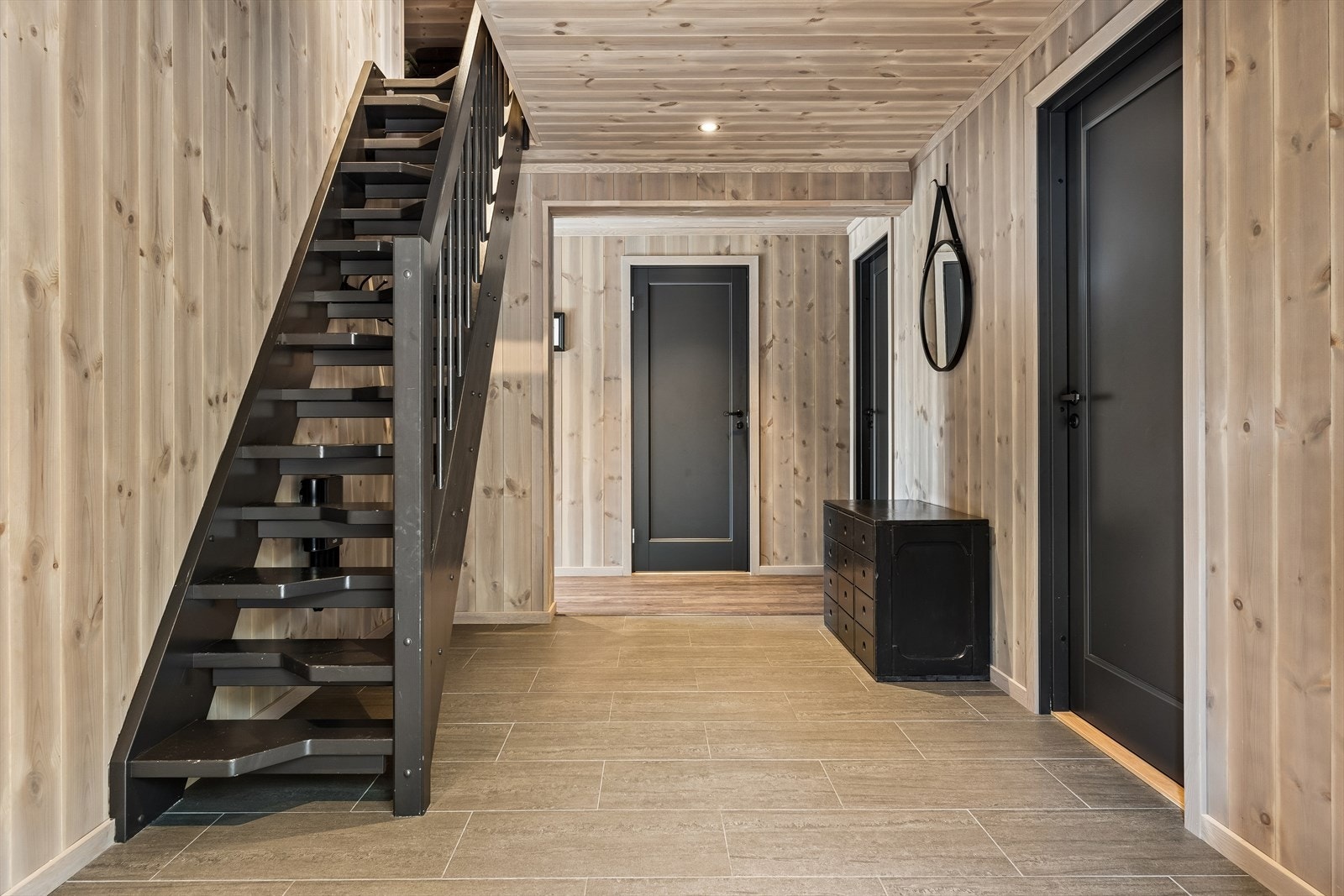 Velkommen inn! Entré med fliser på gulv og tilgang til alle rom i første etasje. Malt trapp leder opp til hemsen. Galleribilde