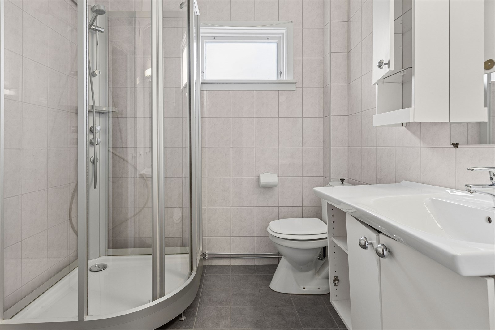 Badet i andre etasje er flislagt og utstyrt med dusjkabinett, servantinnredning og toalett. Galleribilde