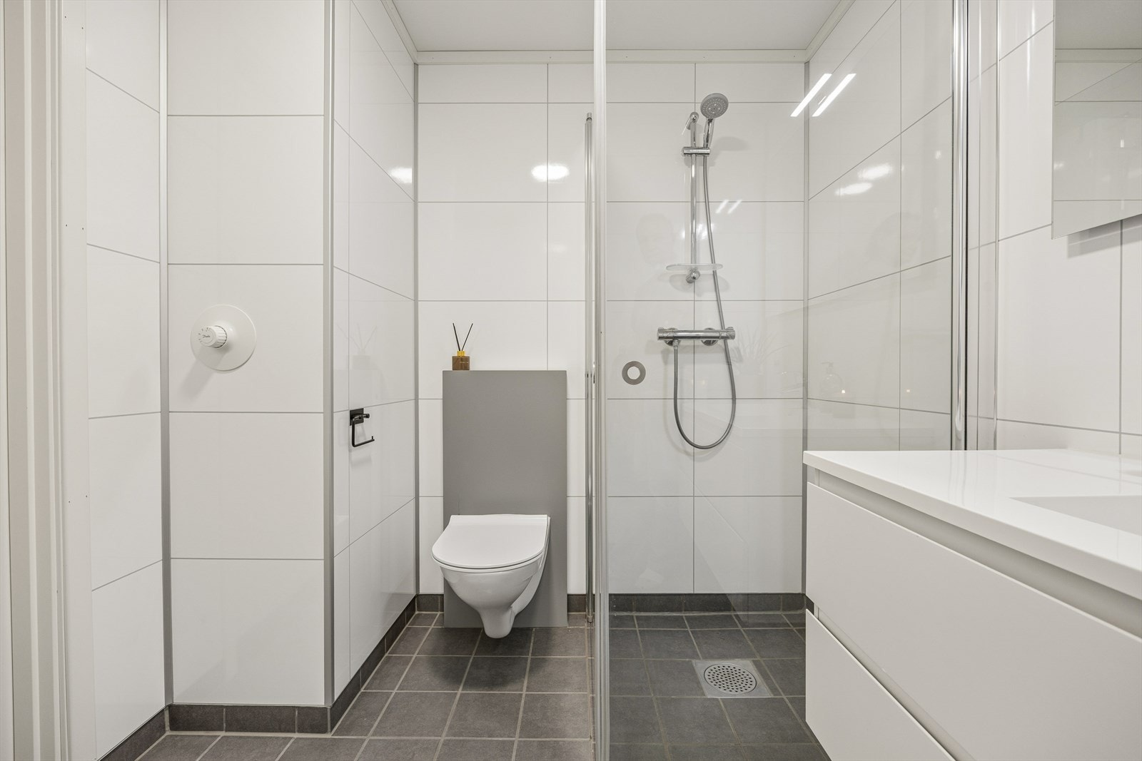 Badet er ellers utstyrt med dusjhjørne, vegghengt toalett og baderomsinnredning med nedfelt servant. Galleribilde