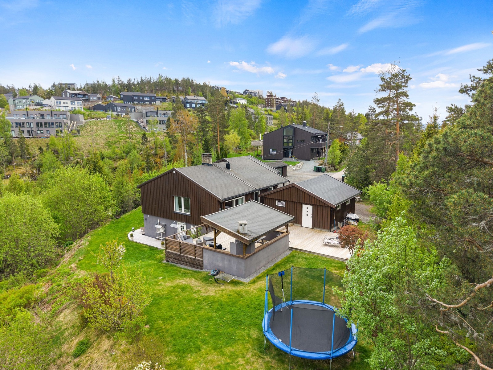 Eiendommen ligger på en skrånende tomt som er pent opparbeidet med plenarealer, hyggelige uteplasser og gruset gårdsplass. Galleribilde