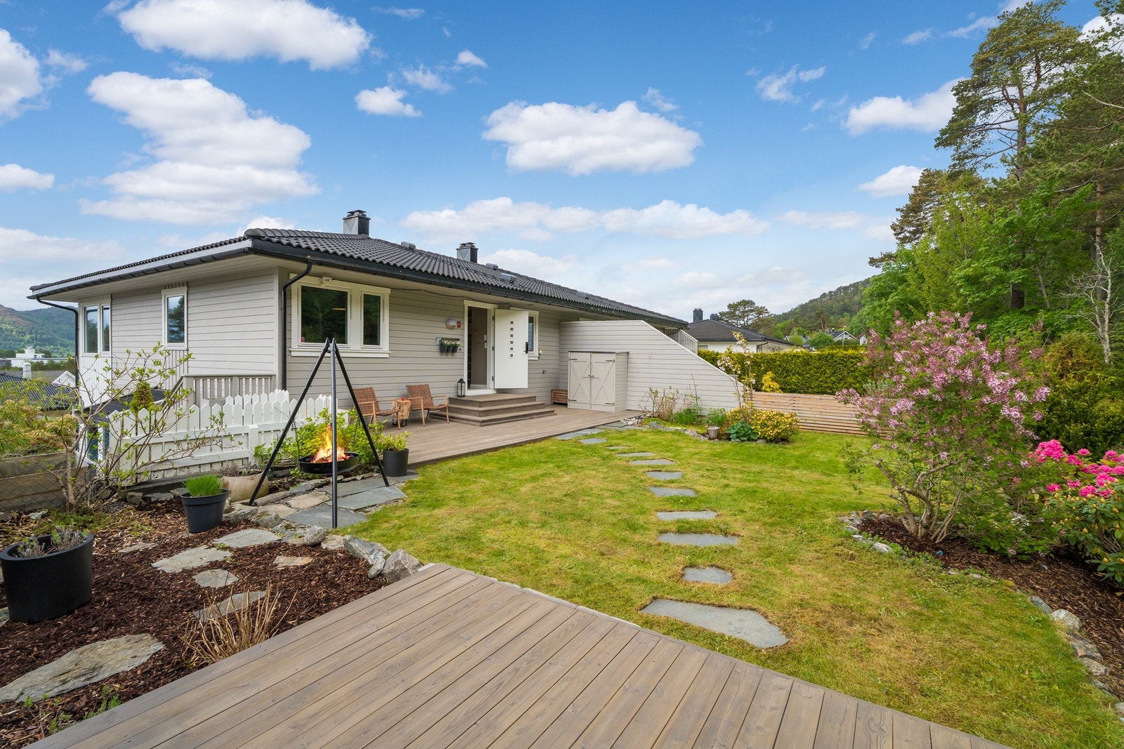 Mot nord er eiendommen pent opparbeidet med beplantning, grøntareal og terrasse. Her er det lagt opp for flotte stunder i sosialt samvær. Galleribilde