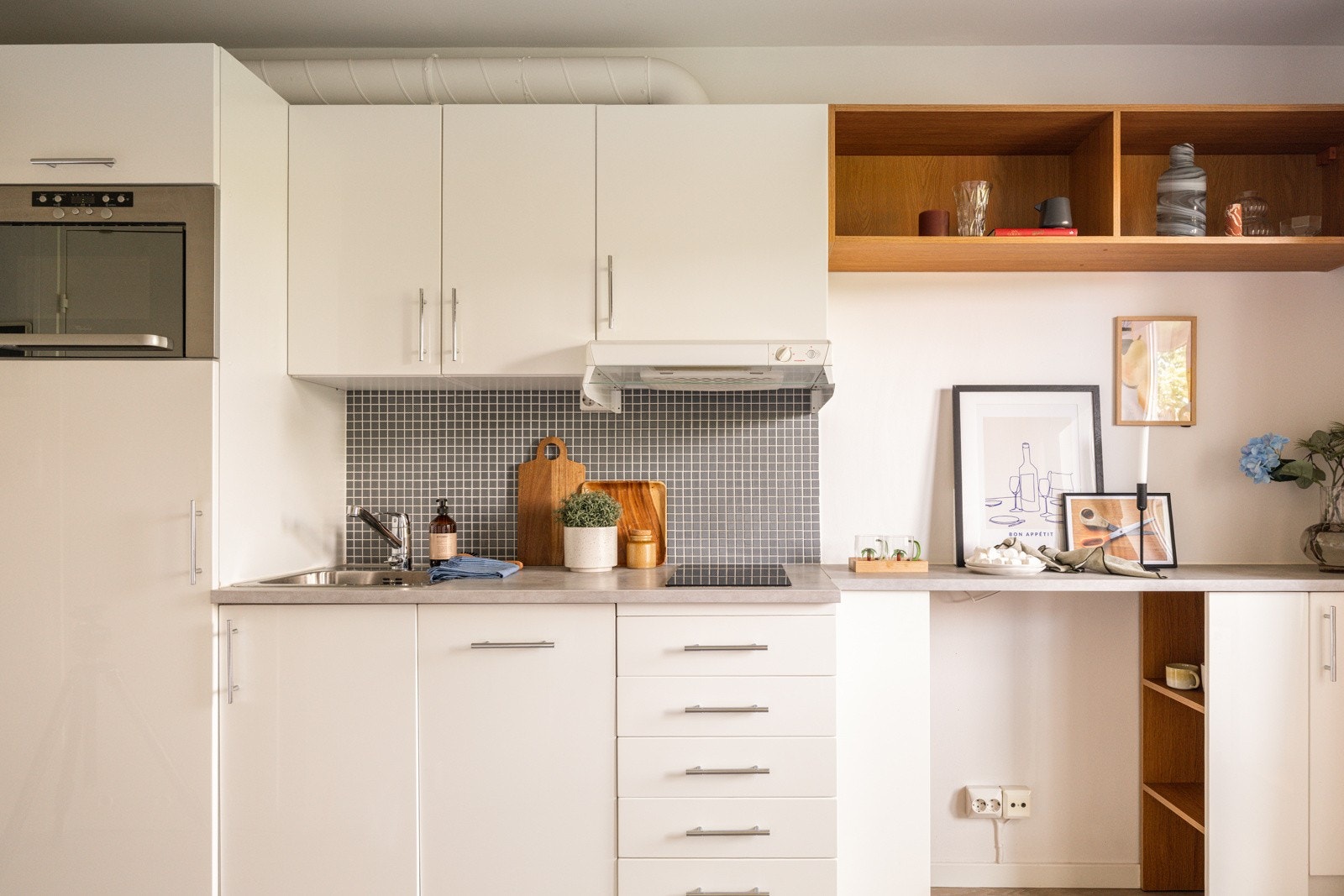 Lys og pen kjøkkeninnredning fra 2008 med hvite glatte fronter og laminert benkeplate med nedfelt oppvaskkum. Galleribilde