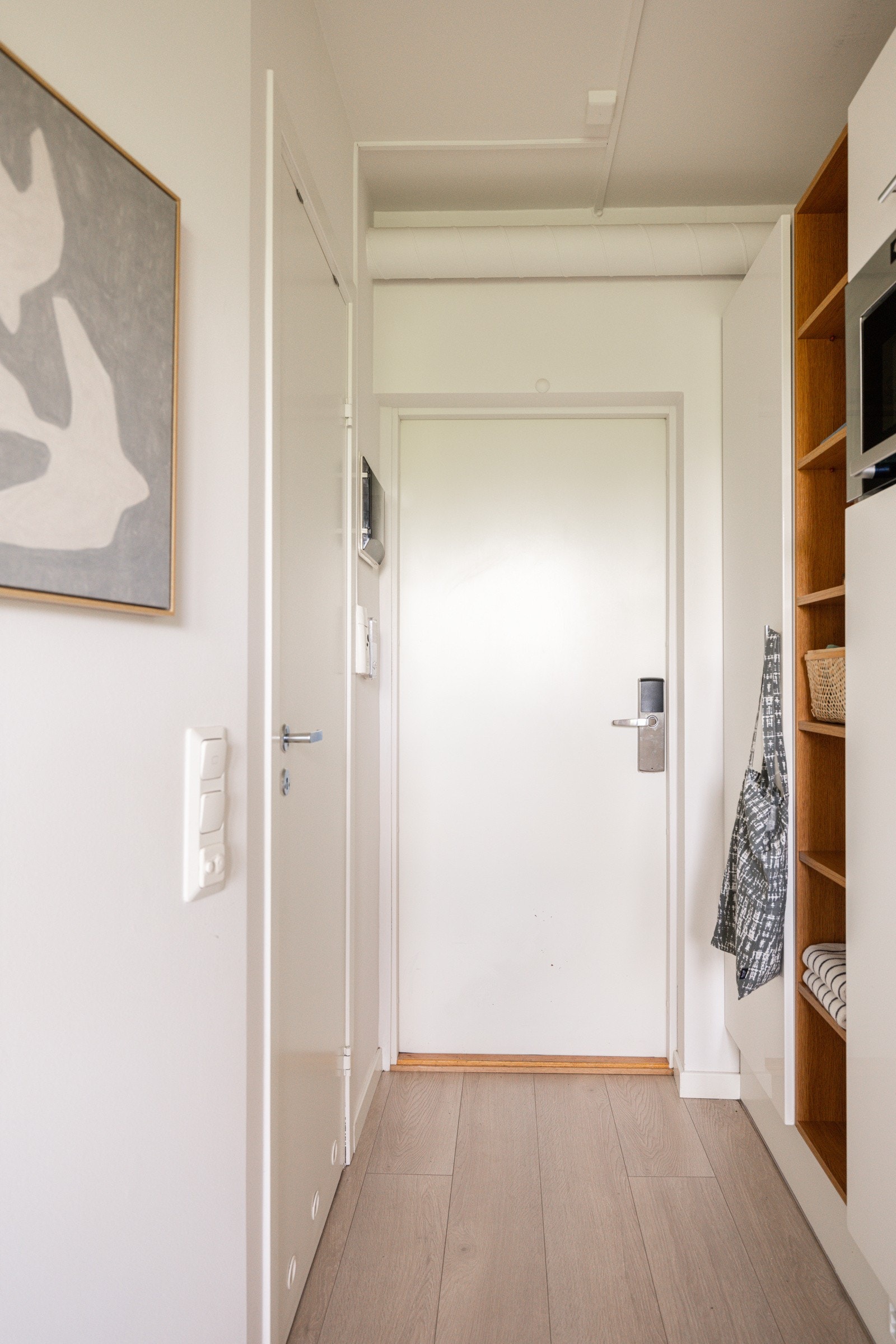 Når du entrer leiligheten har du plass til sko og yttertøy i garderobeskap, samt i åpne trehyller. Porttelefon og sikringsskap med automatsikringer montert på vegg. Galleribilde