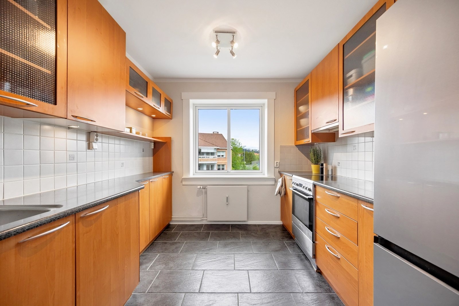 Innredning med finerte fronter, laminatbenkeplate og fliser over benk. Galleribilde