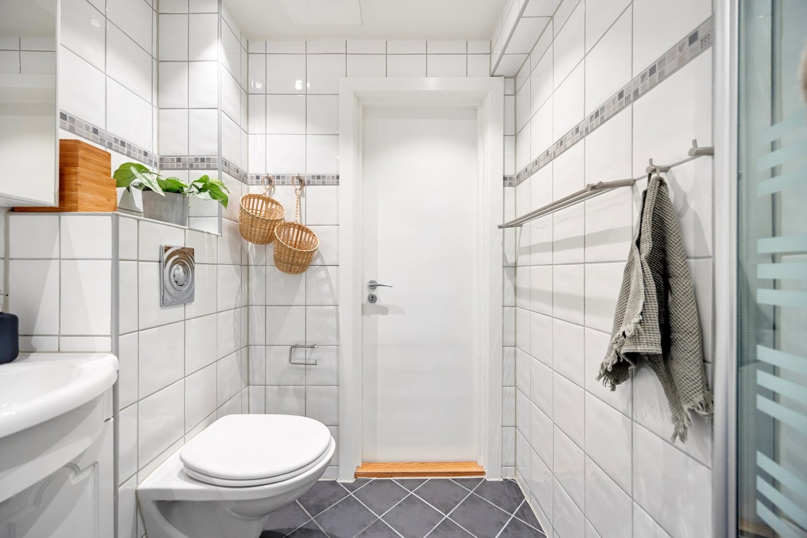 Badet har varmekabler i gulvet, opplegg for vaskemaskin og svingbare dusjvegger i glass. Galleribilde