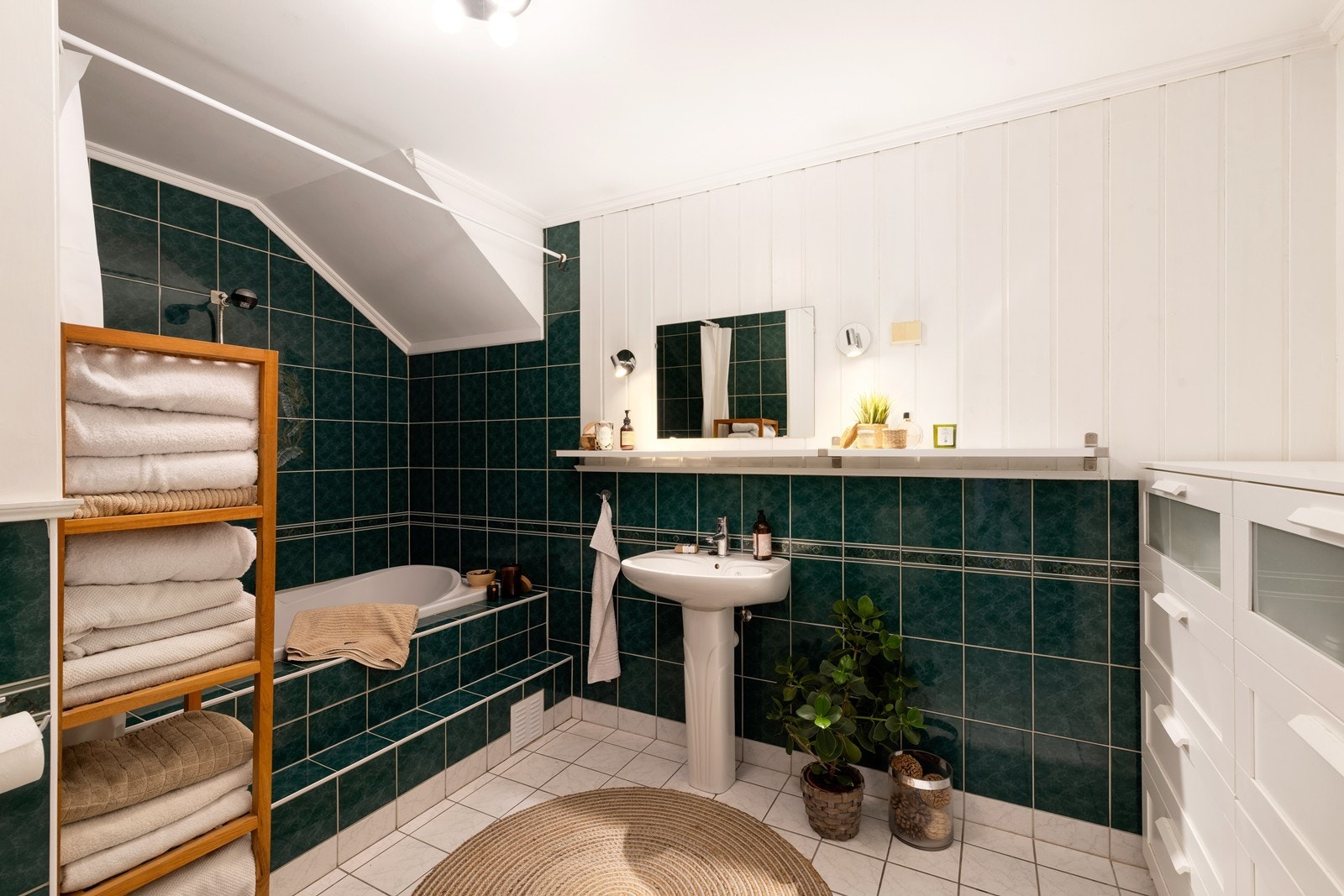 Flislagt bad med innfliset badekar, servant og toalett, vaskerom med belegg på gulv. Galleribilde