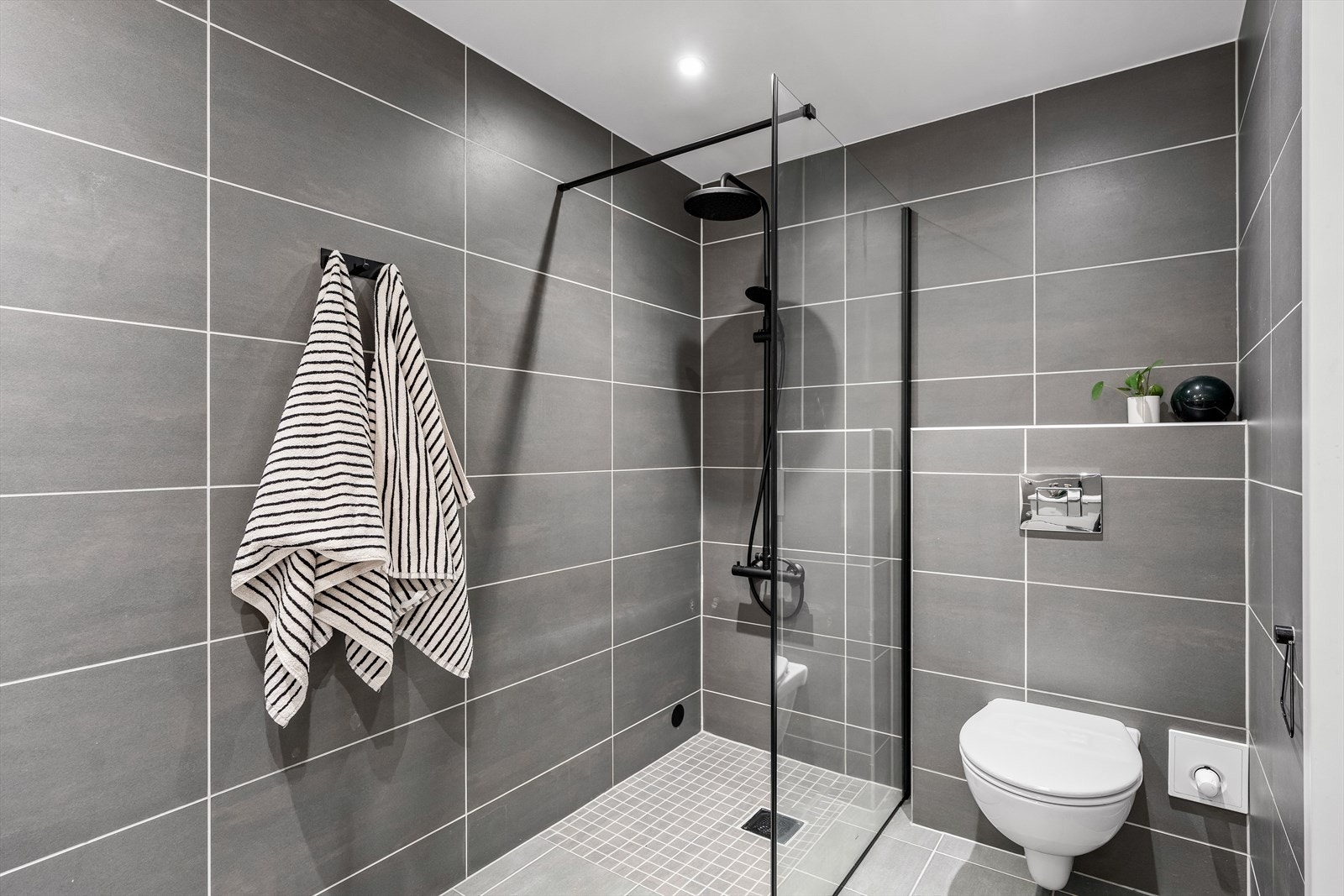 Det er videre innredet med underskap, servant, speil med lys, stikk og en dusjone. Også dette badet har opplegg for vaskemaskin og et vannklosett. Galleribilde