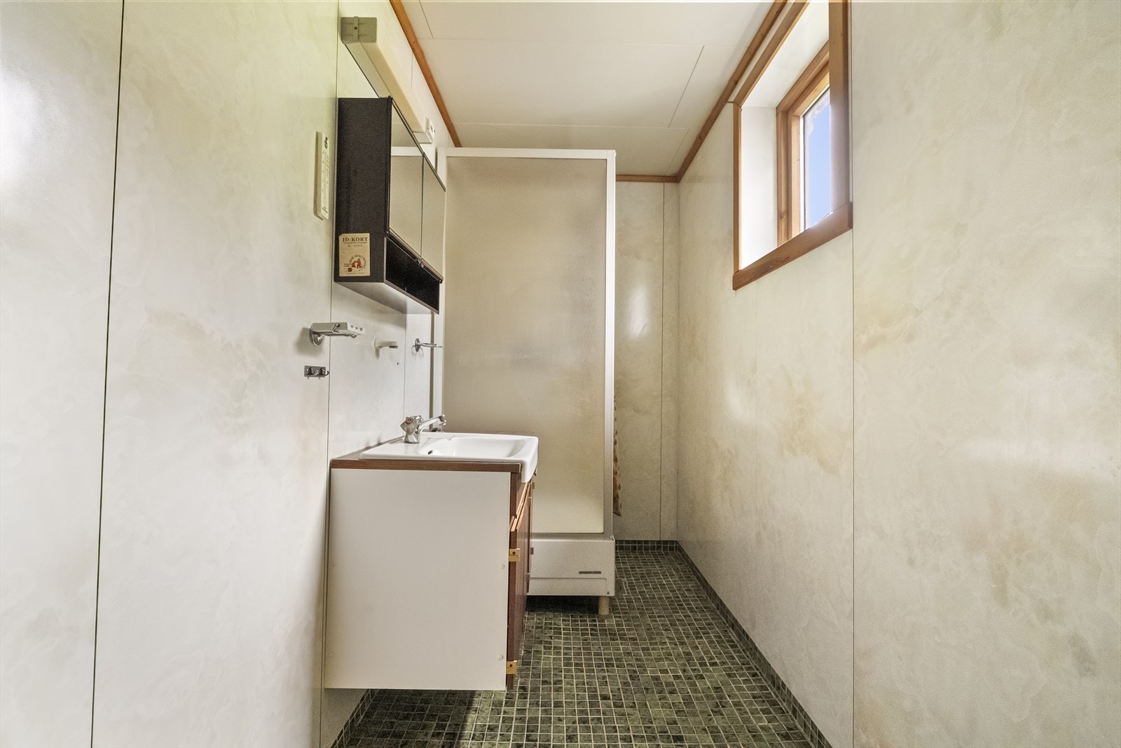 Badet har våtromspanel på veggane, keramisk mosaikkflis på golvet og dusjkabinett. Galleribilde