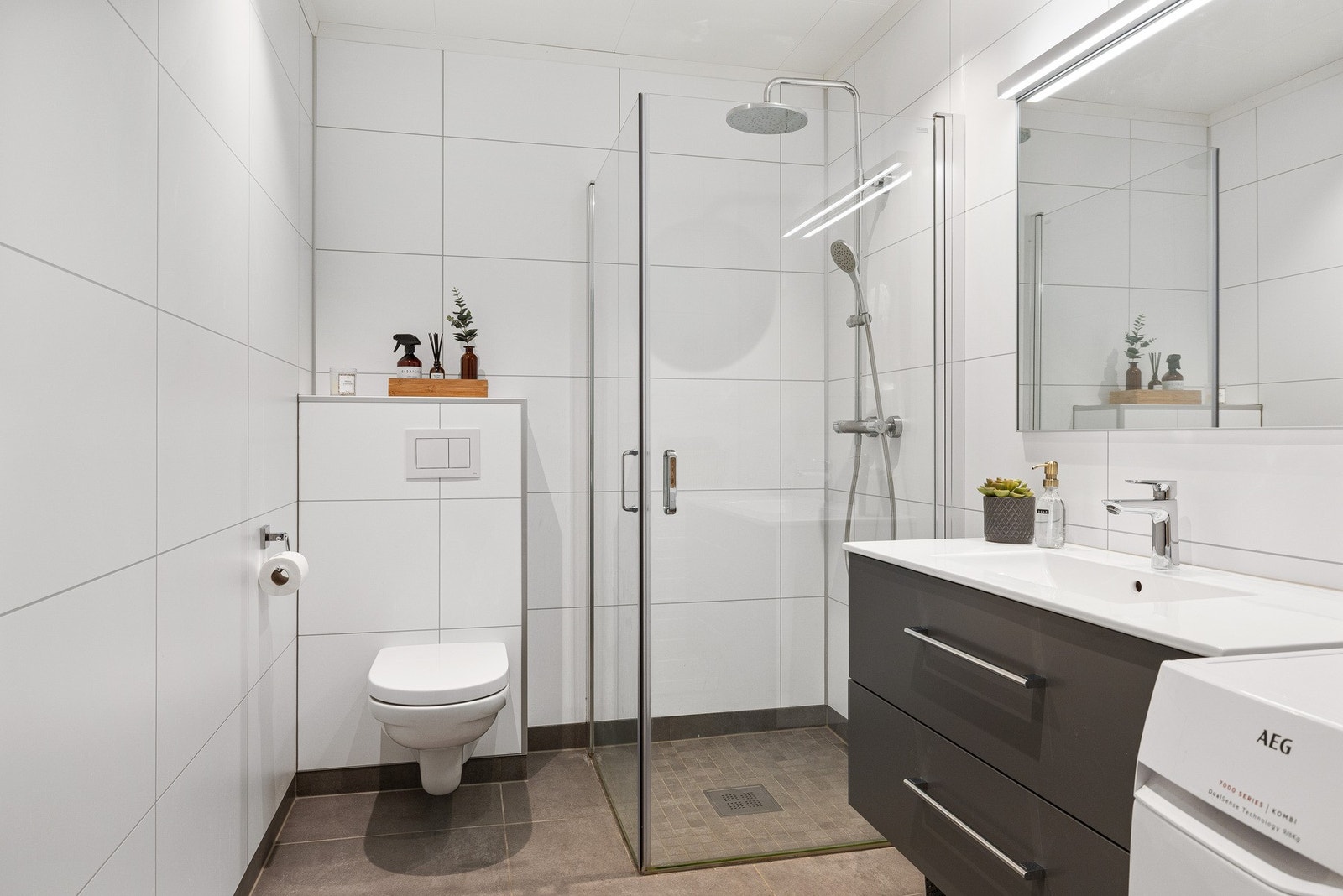 Badet har flislagt gulv og våtromsplater på vegg. Elektriske varmekabler i gulv. Det er opplegg for vaskemaskin. Galleribilde