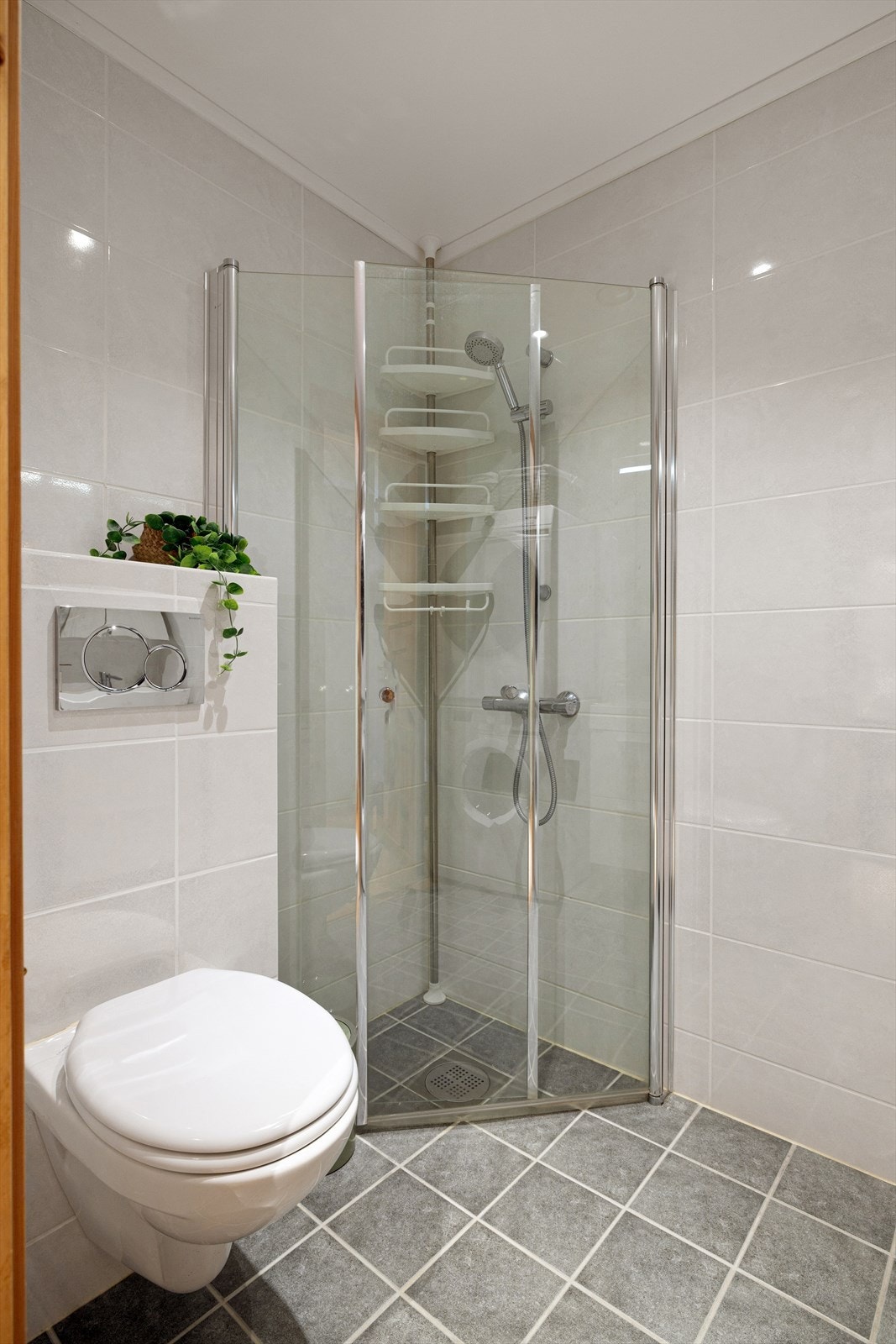 Badet har nedfelt servant med skuffeseksjon, speilskap med lys, veggmontert toalett, dusjhjørne med innfellbare glassvegger, og opplegg for vaskemaskin og tørketrommel. Galleribilde