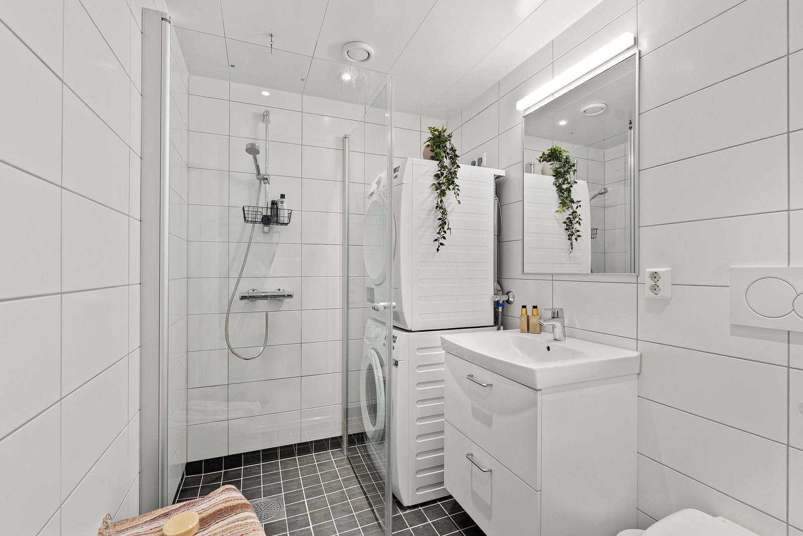 Lekkert flislagt bad med gulvvarme, vegghengt toalett, dusjhjørne og opplegg for vaskemaskin- downlights i himling. Galleribilde