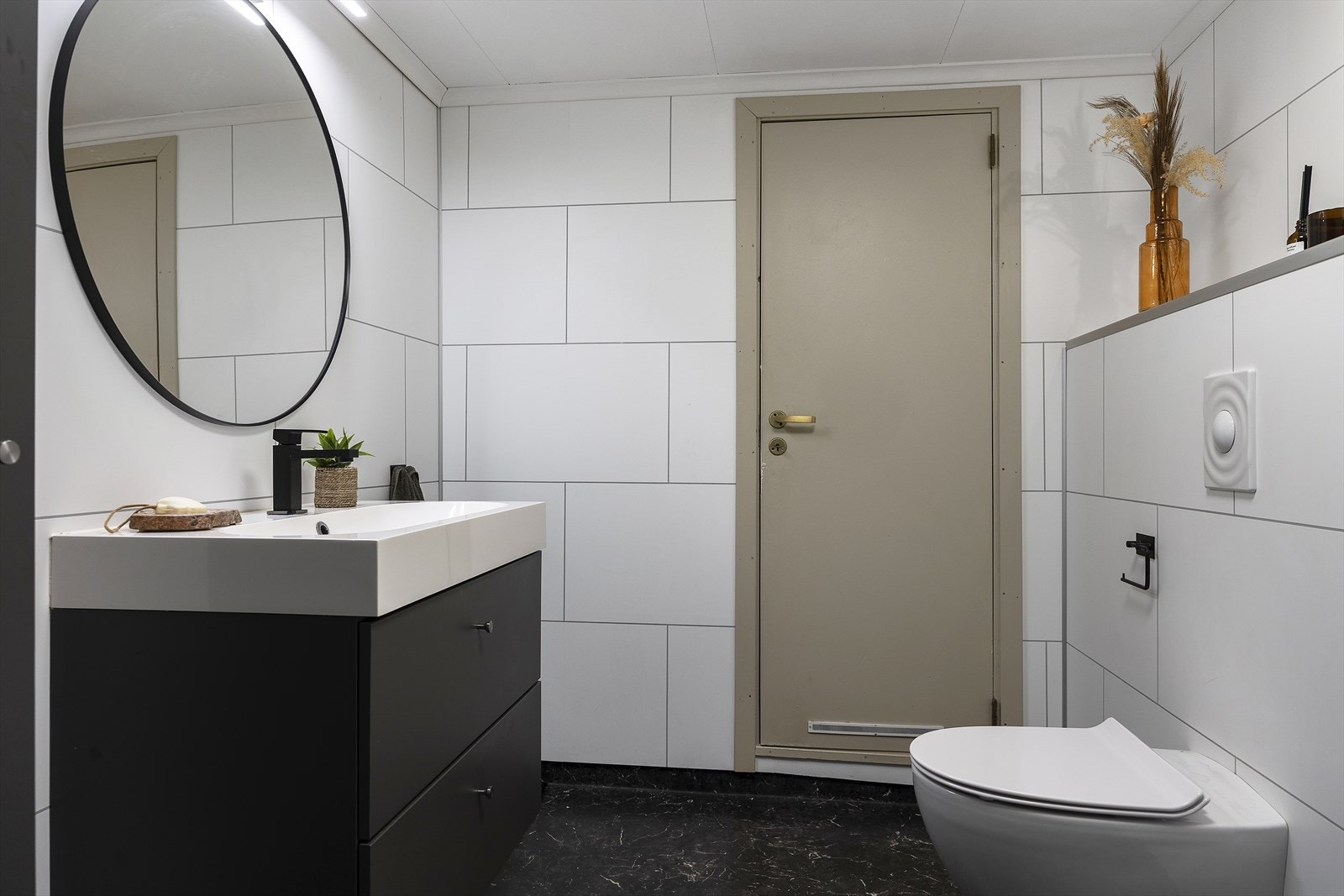 Badet er utstyrt med vegghengt toalett, dusjhjørne med glassdører og innredning med servant. Galleribilde