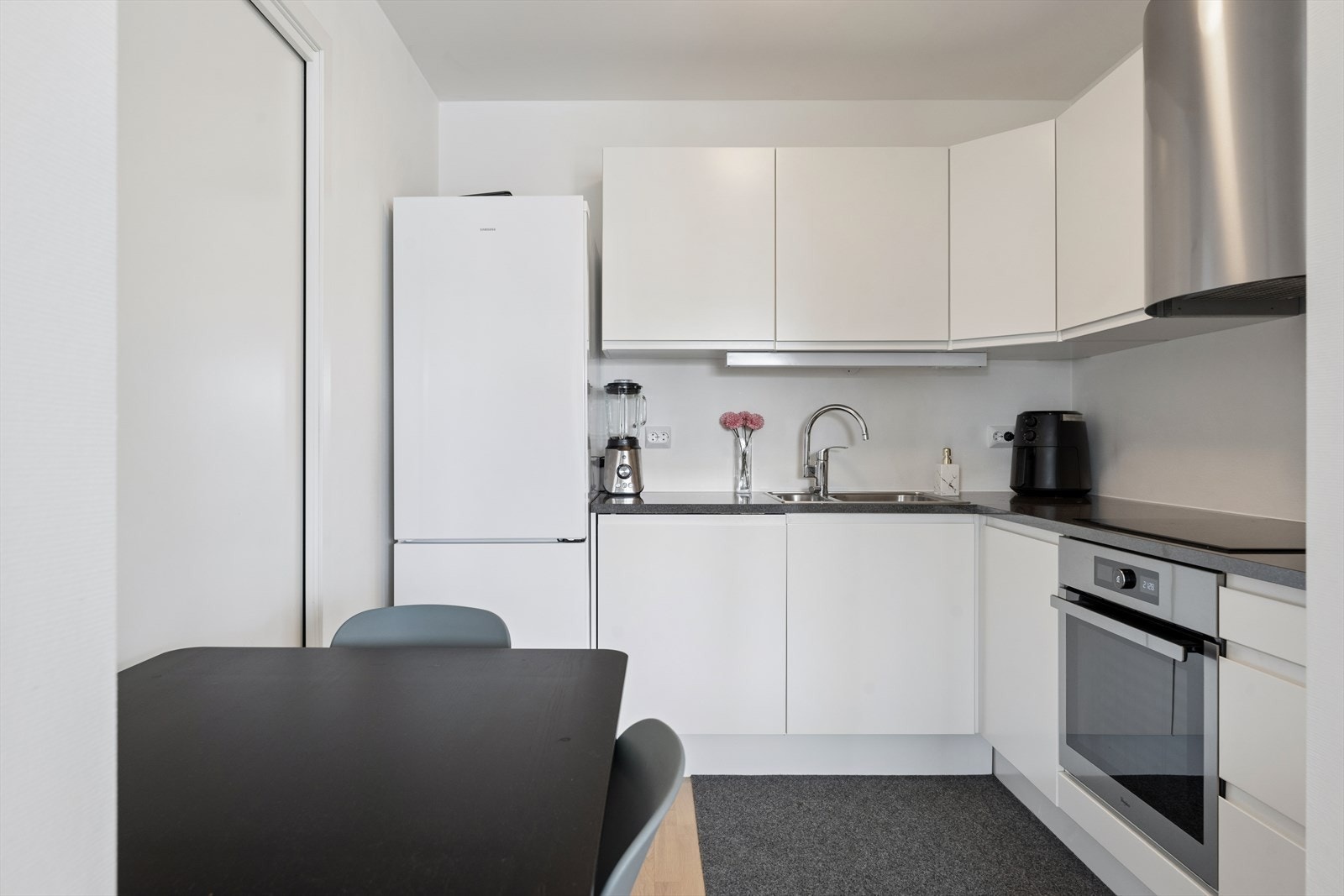 Kjøkkeninnredning fra Norema med slette fronter, laminatbenkeplate og integrerte hvitevarer. Galleribilde