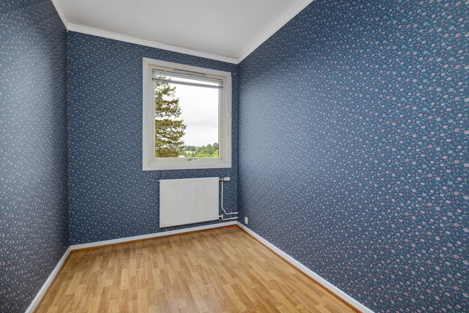 Også her sørger en radiator for jevn varme, og rommet har overflater med tapet. Galleribilde