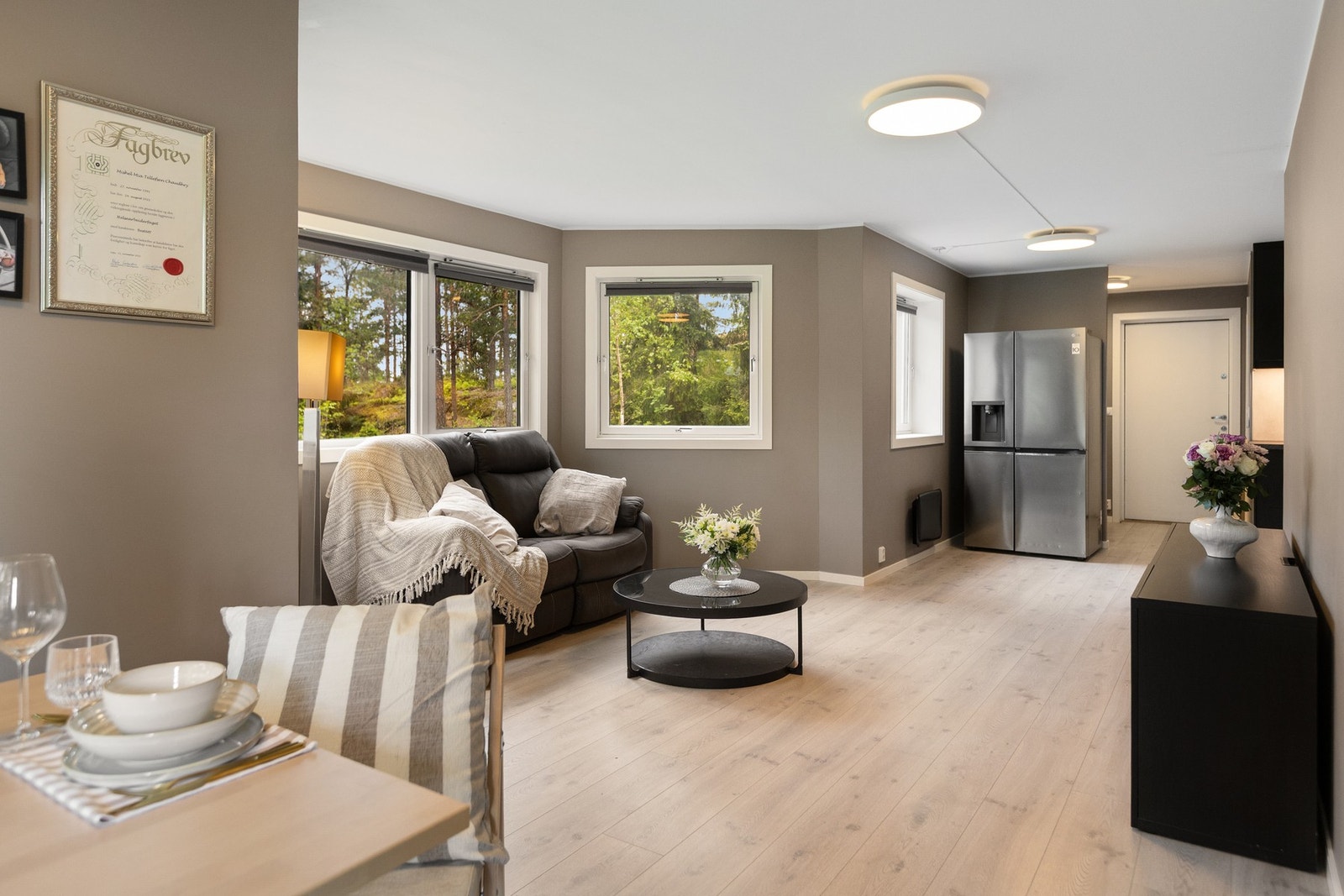 Innbydende stue med store vinduer som slipper inn rikelig med naturlig lys og gir utsyn mot grønne omgivelser. Galleribilde