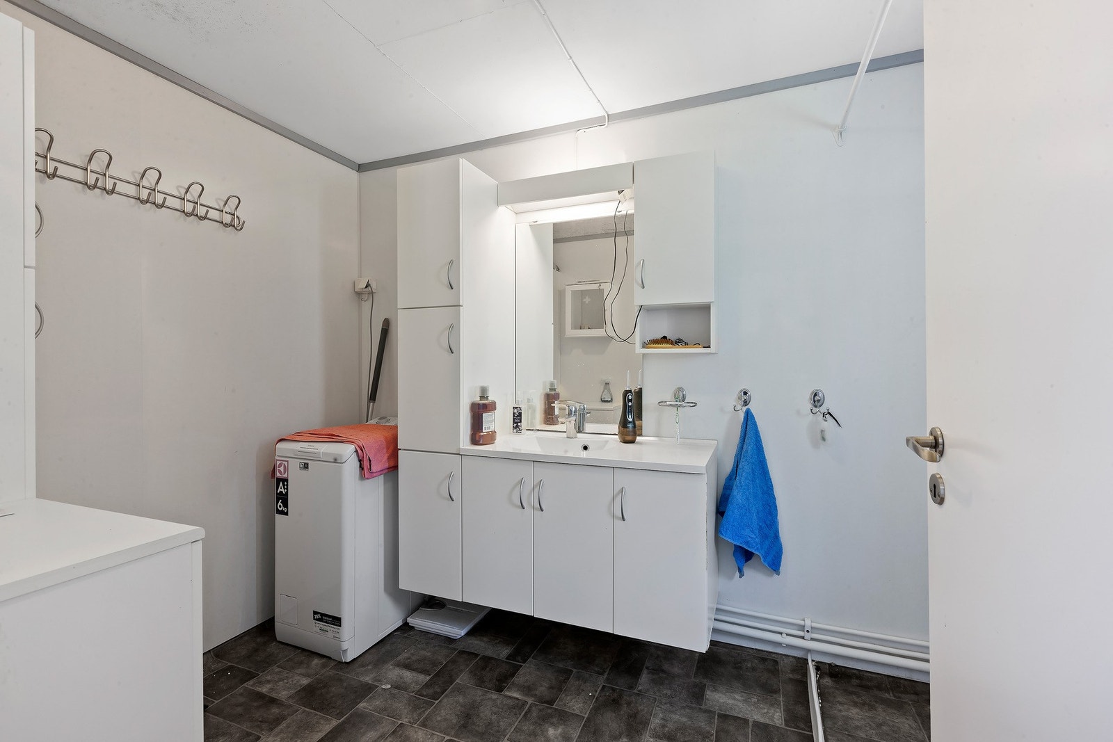 Badet har lys innredning med nedfelt servant og skap under, overskap og speil med lys over, dusjnisje og opplegg for vaskemaskin. Varme i gulv. Galleribilde