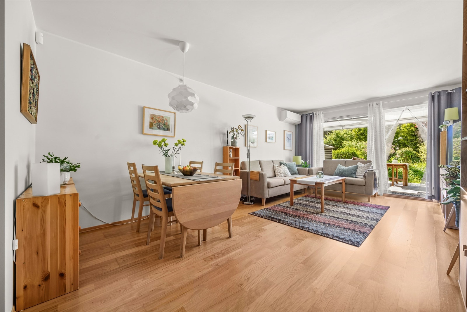 Lys og romslig stue med god plass til både spisebord og sittegruppe, varmepumpe fra 2023 og direkte utgang til den solrike terrassen. Foto: Martine Eren Jacobsen Galleribilde