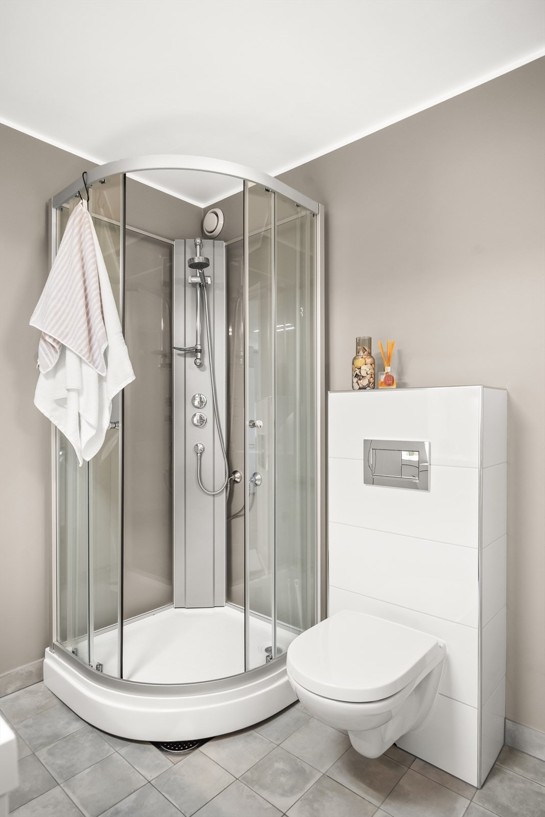 Badet er utstyrt med dusjkabinett med skyvedører i glass og vegghengt toalett med innebygget sisterne. Galleribilde