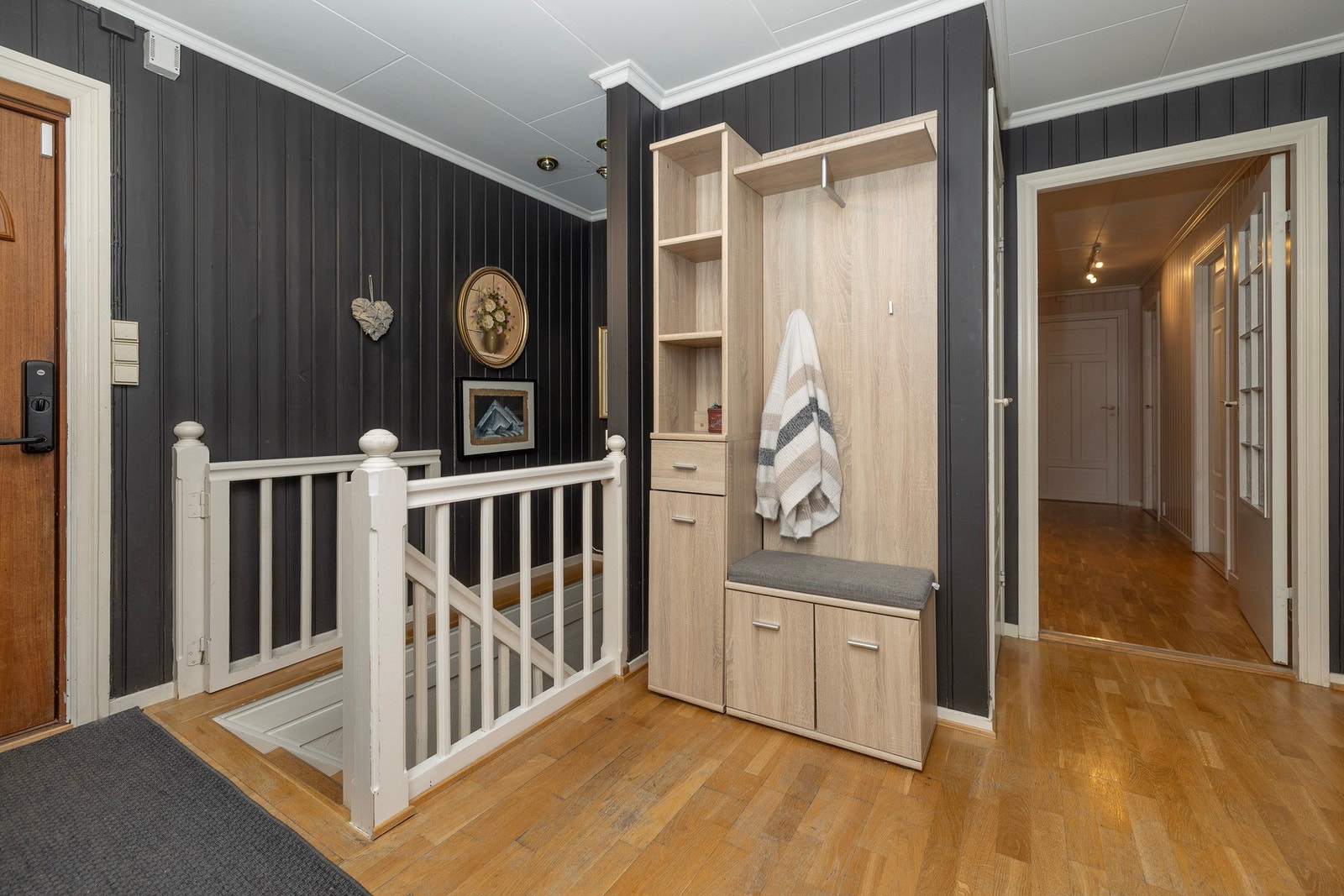 Romslig entrè. Nedgang til kjelleretasje. Soveroms gang sees til høyre i bildet. Galleribilde
