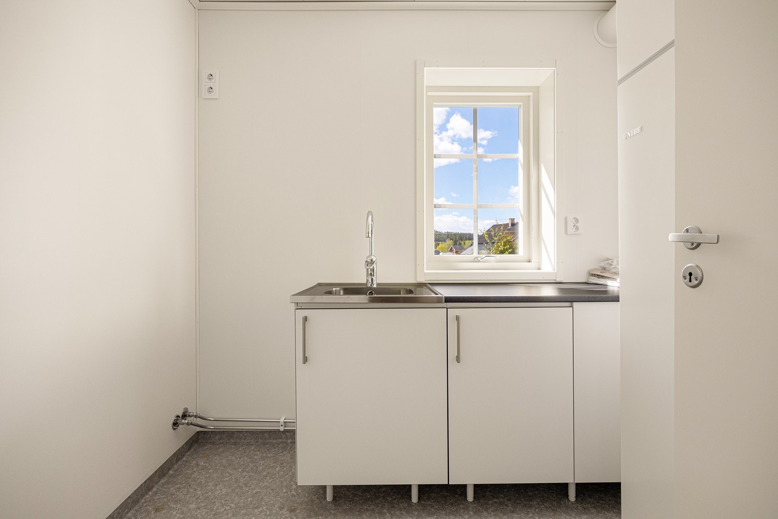 Vaskerommet er funksjonelt innredet med arbeidsbenk, utslagskum, skapplass og opplegg for vaskemaskin. Galleribilde