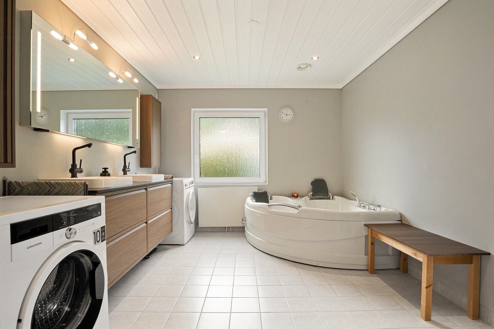 Badet er på 14m², og har plass til vaskemaskin og tørketrommel. Her er badekar, dobbel servant, og speil med møbel. Galleribilde