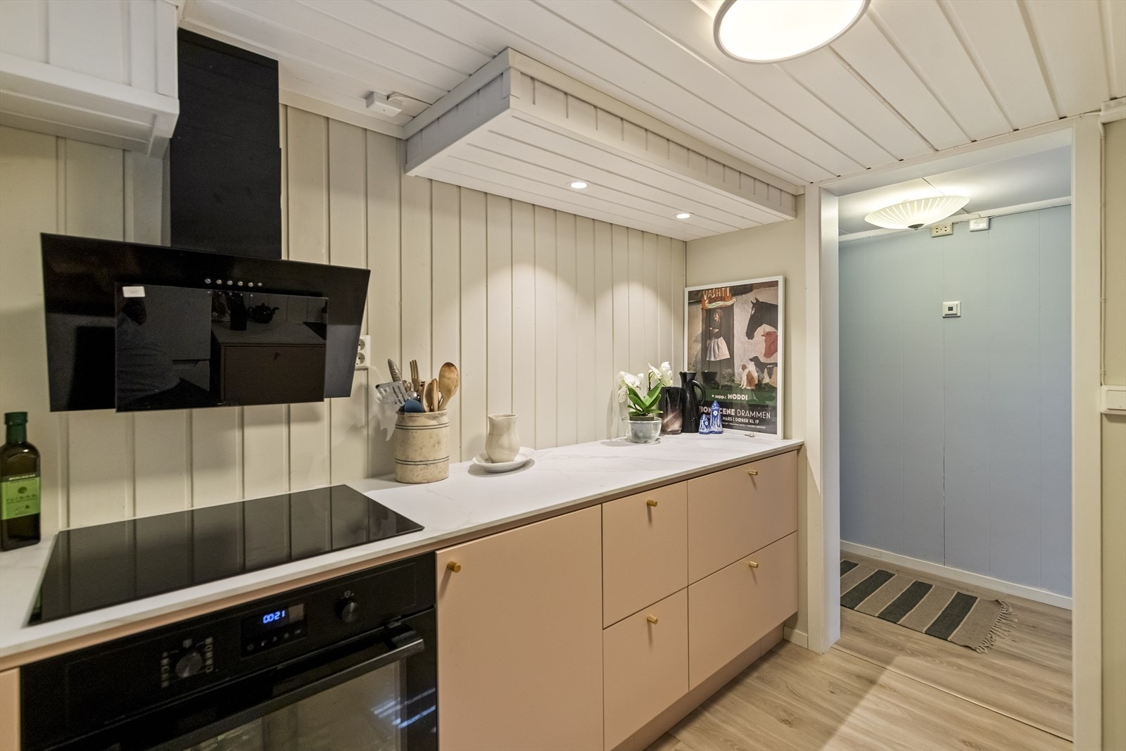 Det har slette fronter i en trendy og lun fargetone, en flott marmor-mønstret benkeplate og moderne integrerte hvitevarer som stekeovn, induksjonstopp og oppvaskmaskin. Galleribilde