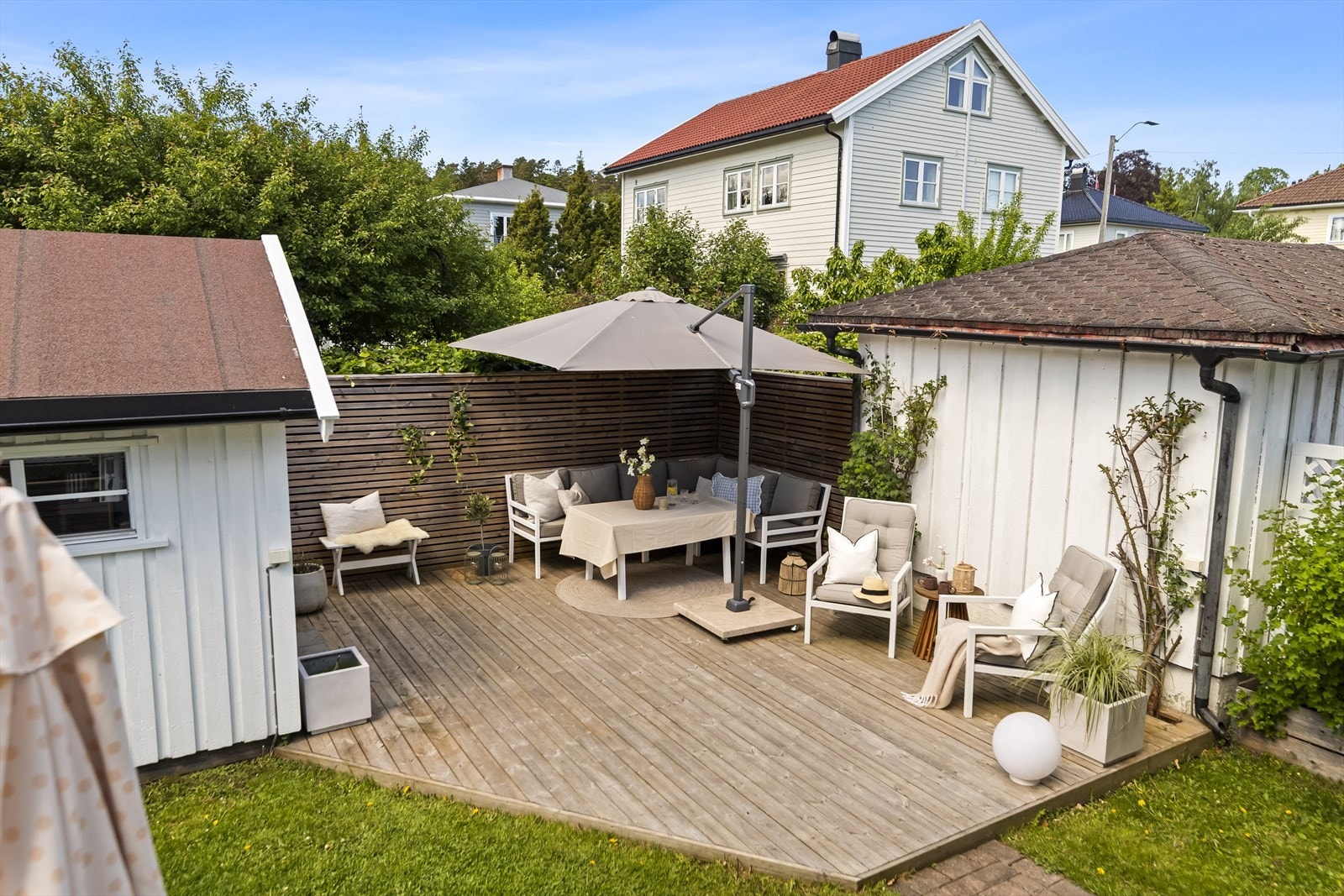 I tillegg til den vestvendte terrassen fra stuen, er det etablert en stor, koselig og usjenert treplatting nede i hagen som innbyr til hyggelige stunder med grill og utemøbler, skjermet av et pent trespilepanel. Galleribilde