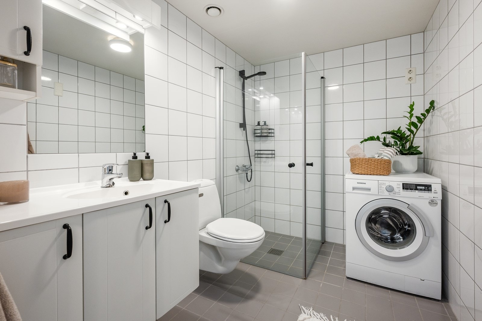 Badet er utstyrt med servant med ettgreps blandebatteri, vegghengt toalett og dusjnisje med innfellbare glassdører Galleribilde