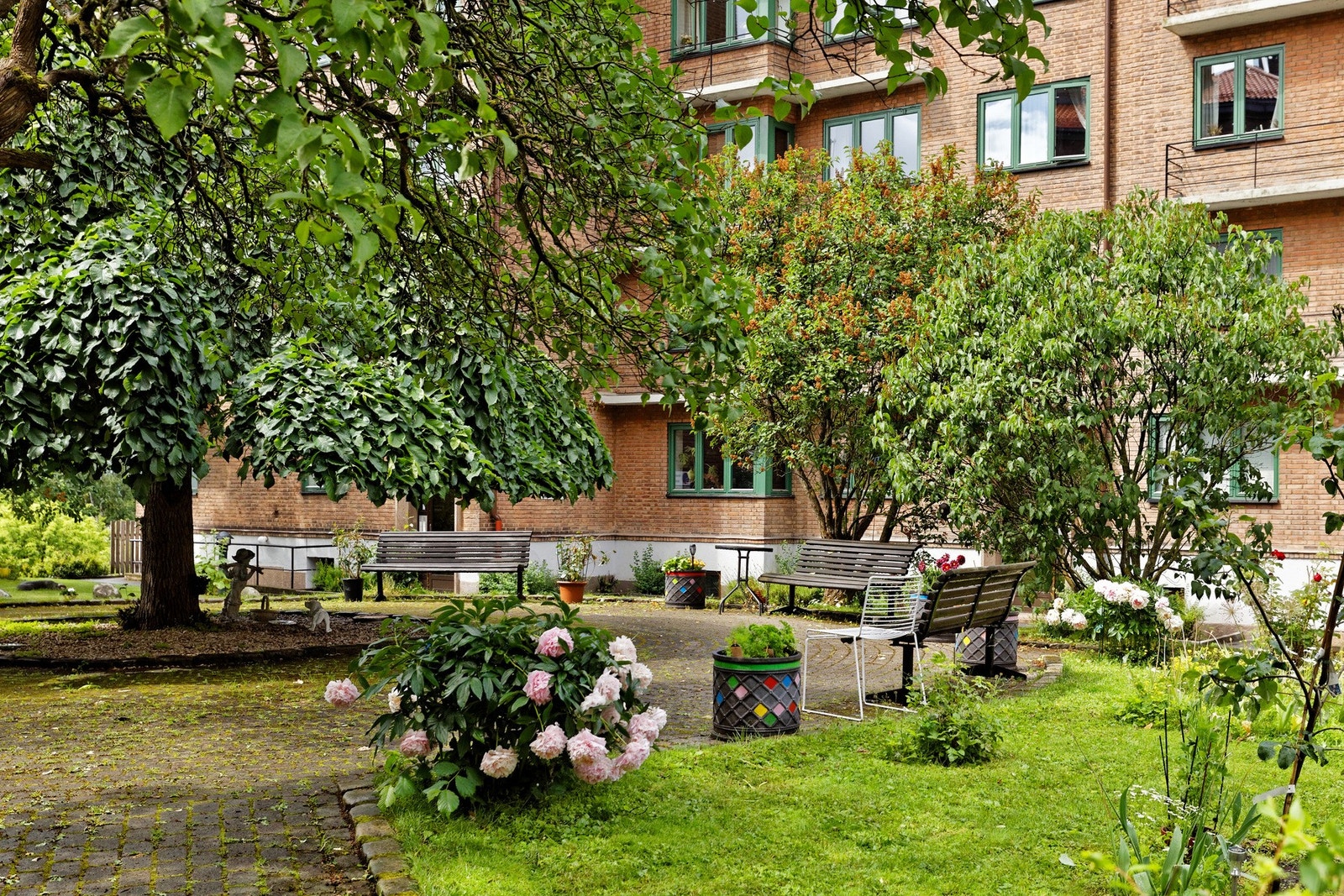 Variert beplantning tilfører bakgården en vakker og fargerik atmosfære. En herlig inngang til leiligheten. Galleribilde