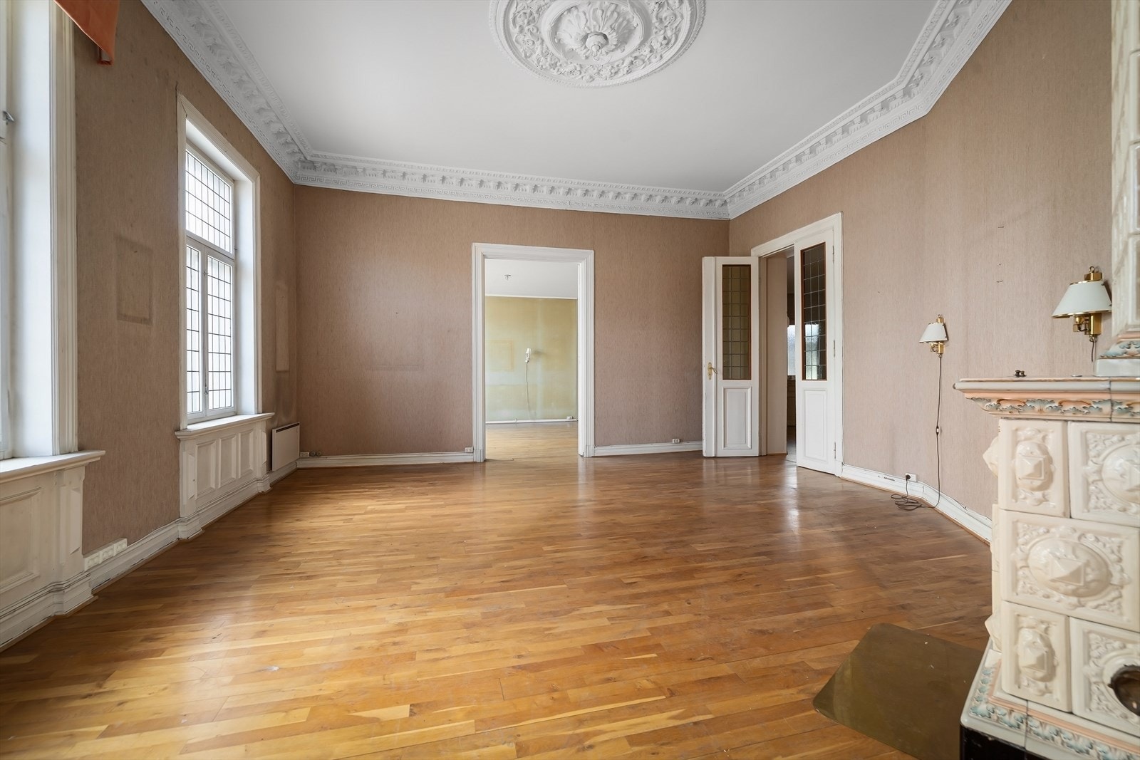 Stuens tak er prydet med stukkatur og en klassisk rosett, som understreker byggeårets sjarm. Galleribilde