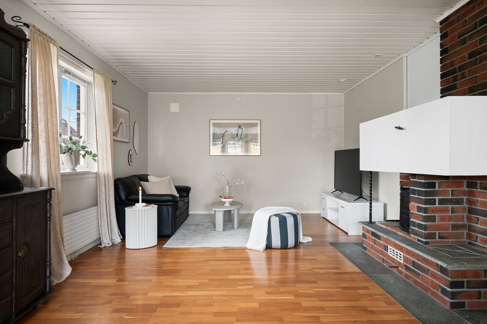 Stuen har parkett på gulvet og malt trepanel i himlingen, noe som gir en klassisk ramme. Galleribilde