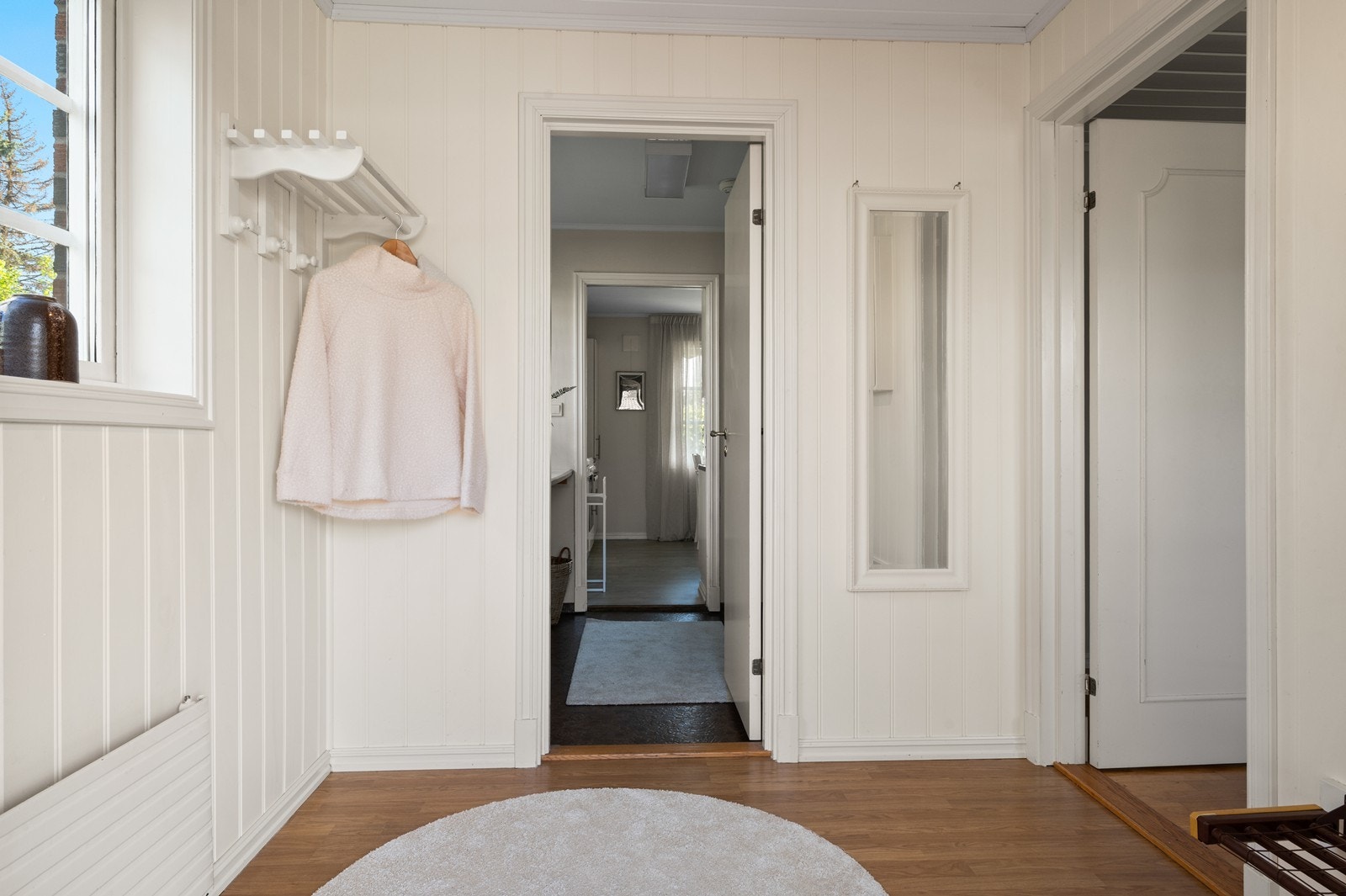 Entréen har parkett på gulvet og gir adkomst til et praktisk vaskerom og videre inn i boligen. Galleribilde