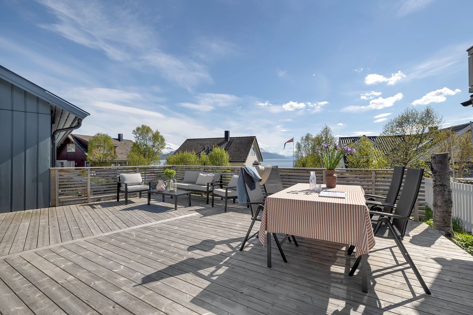Sørvendt skjermet terrasse bak garasje med rikelig plass for utemøblering. Galleribilde