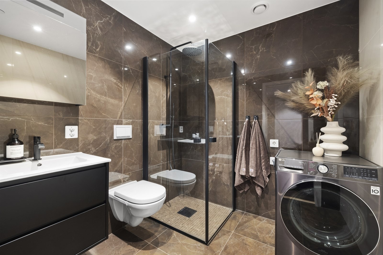 Badet er et delikat, påkostet og moderne rom. Vegger og gulv er kledd med store, lekre fliser i en rolig fargetone som gir en behagelig og eksklusiv spafølelse. Galleribilde