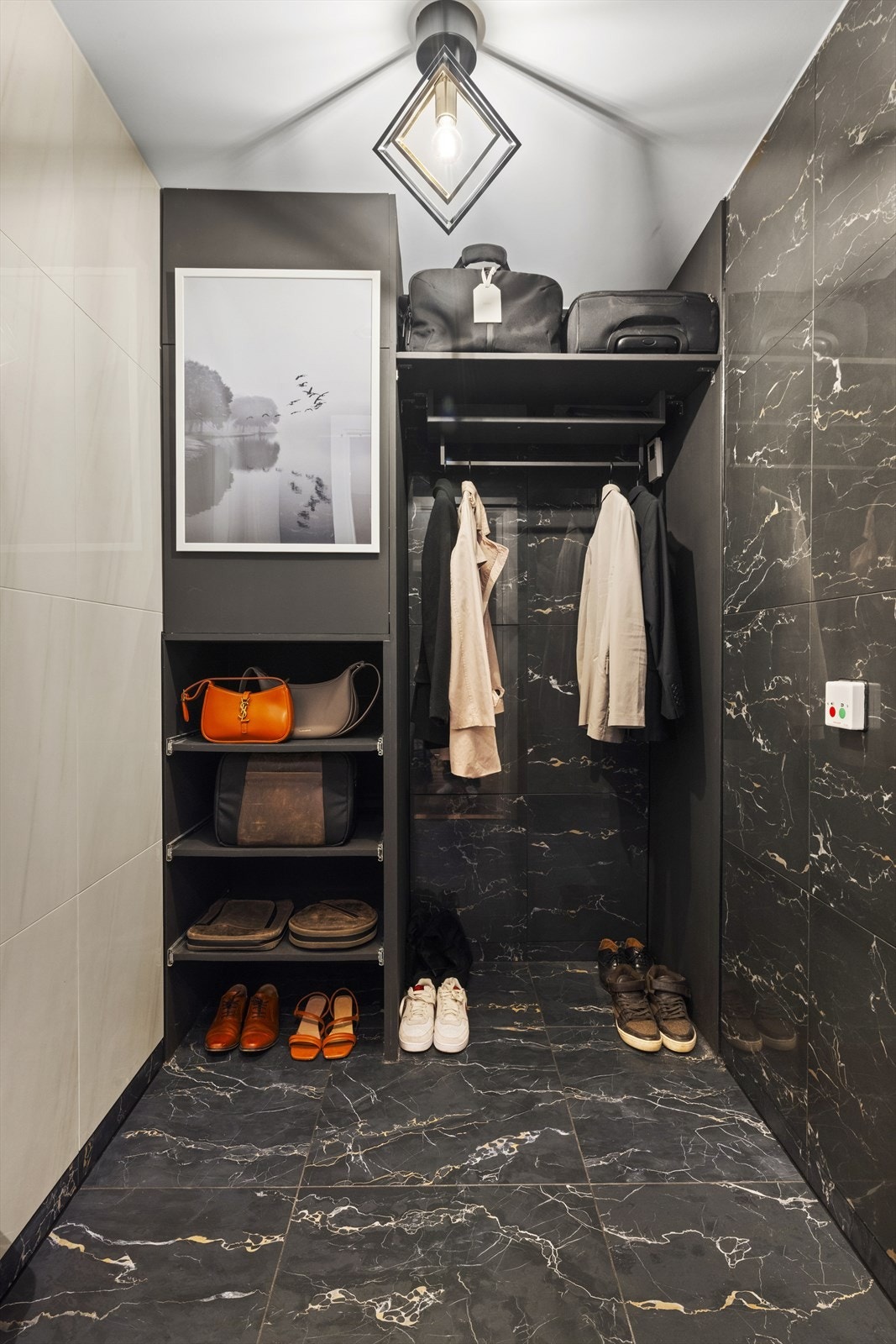 Rett fra entréen har du adkomst til et påkostet garderoberom (walk-in closet). Dette rommet skiller seg ut med eksklusive fliser på både vegger og gulv som ligner mørk og elegant marmor. Galleribilde