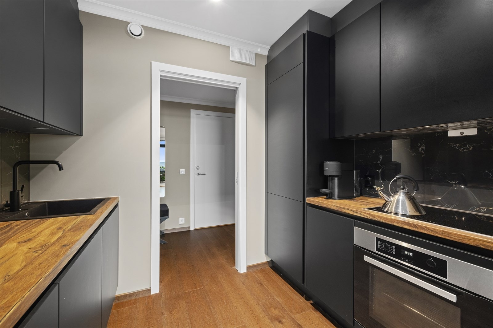 Mellom benkeplaten og overskapene er det backsplash i sort marmoretterligning. Dette gjør at den eksklusive marmorstilen fra resten av boligen gjentas og fullfører det helhetlige designet. Kjøkkenet er utstyrt med integrerte kvalitetshvitevarer. Galleribilde