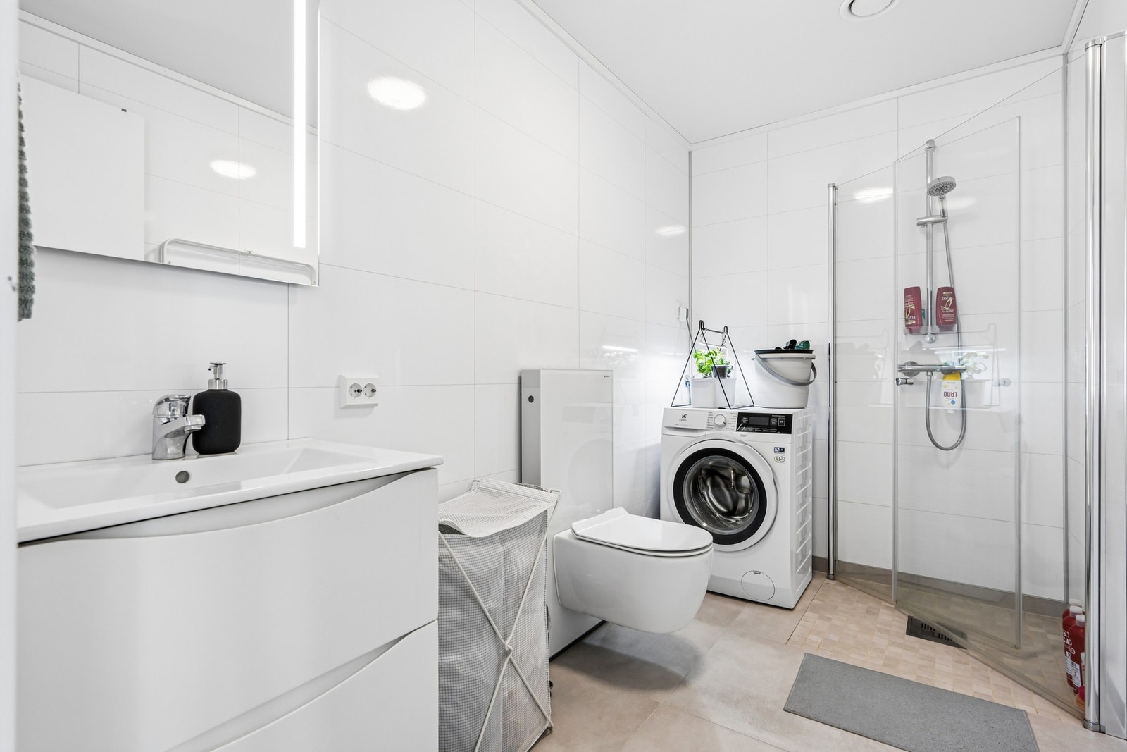 Badet har flislagt gulv med varmekabler, våtromsplater på veggene og opplegg for vaskemaskin. Galleribilde