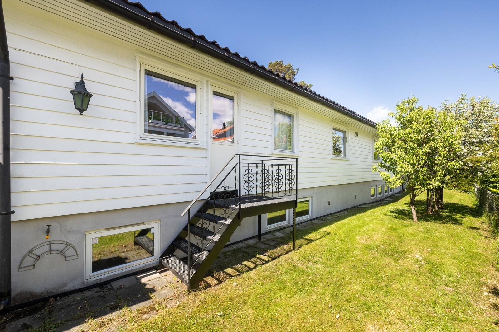 Utgang fra hovedsoverom til hage på bakside av huset - tilknytning til markterrasse bak garasje med morgenssol Galleribilde