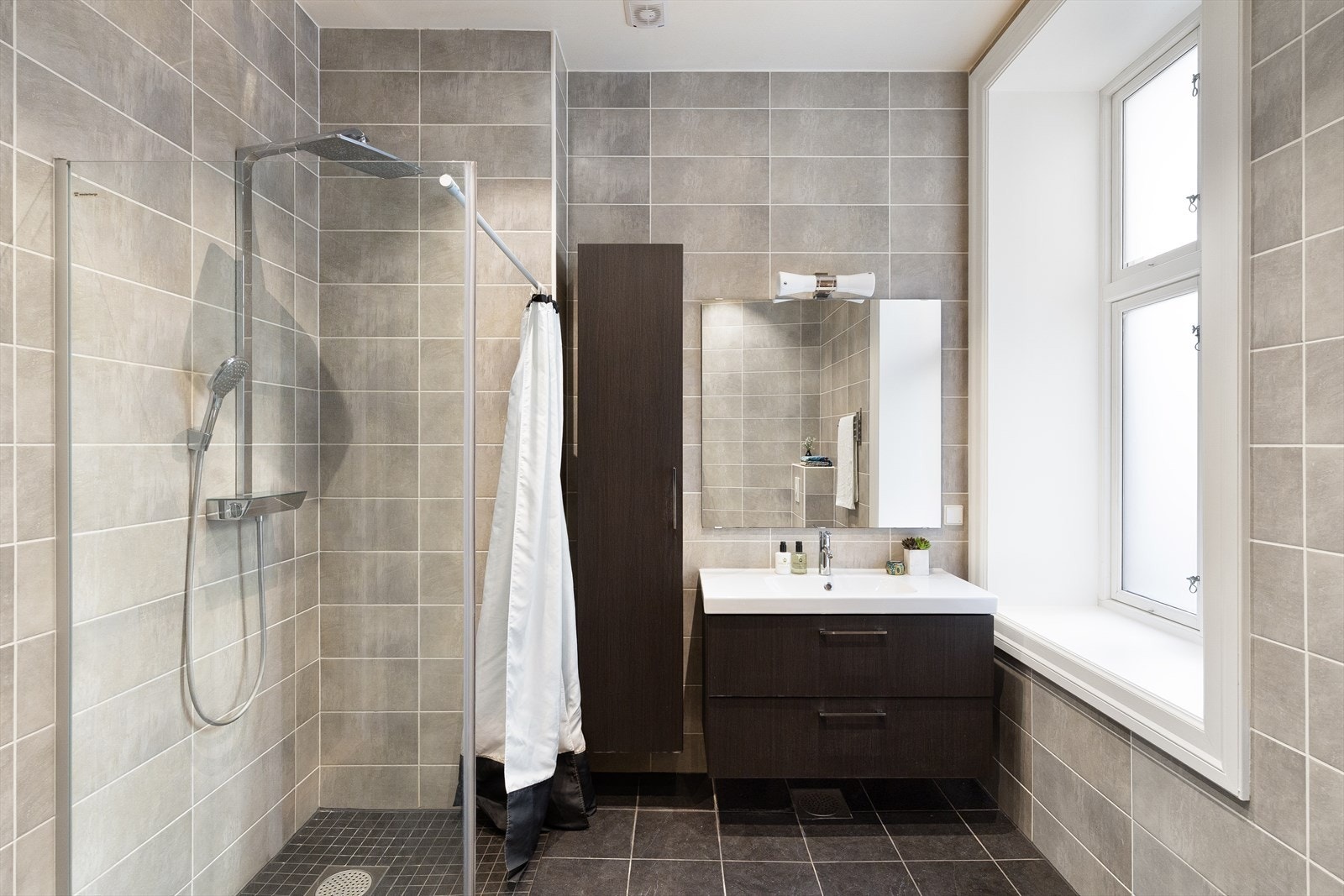 Badet er utstyrt med dusjnisje, vegghengt toalett, servantskap med ettgreps blandebatteri og mekanisk avtrekk. Galleribilde