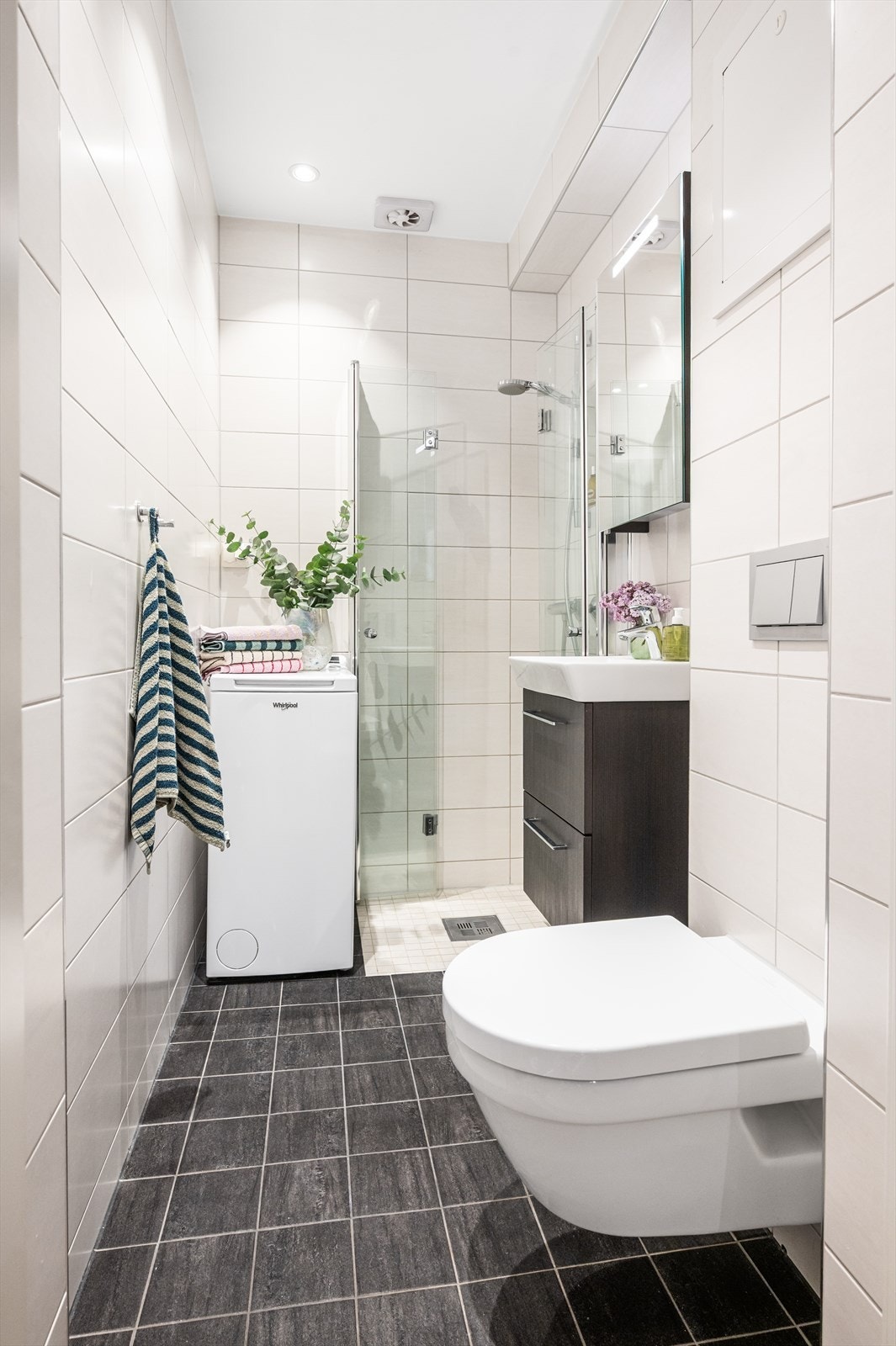Badet er innredet med vegghengt toalett, servant i innredning og dusjhjørne med svingbare foldeglass. Galleribilde