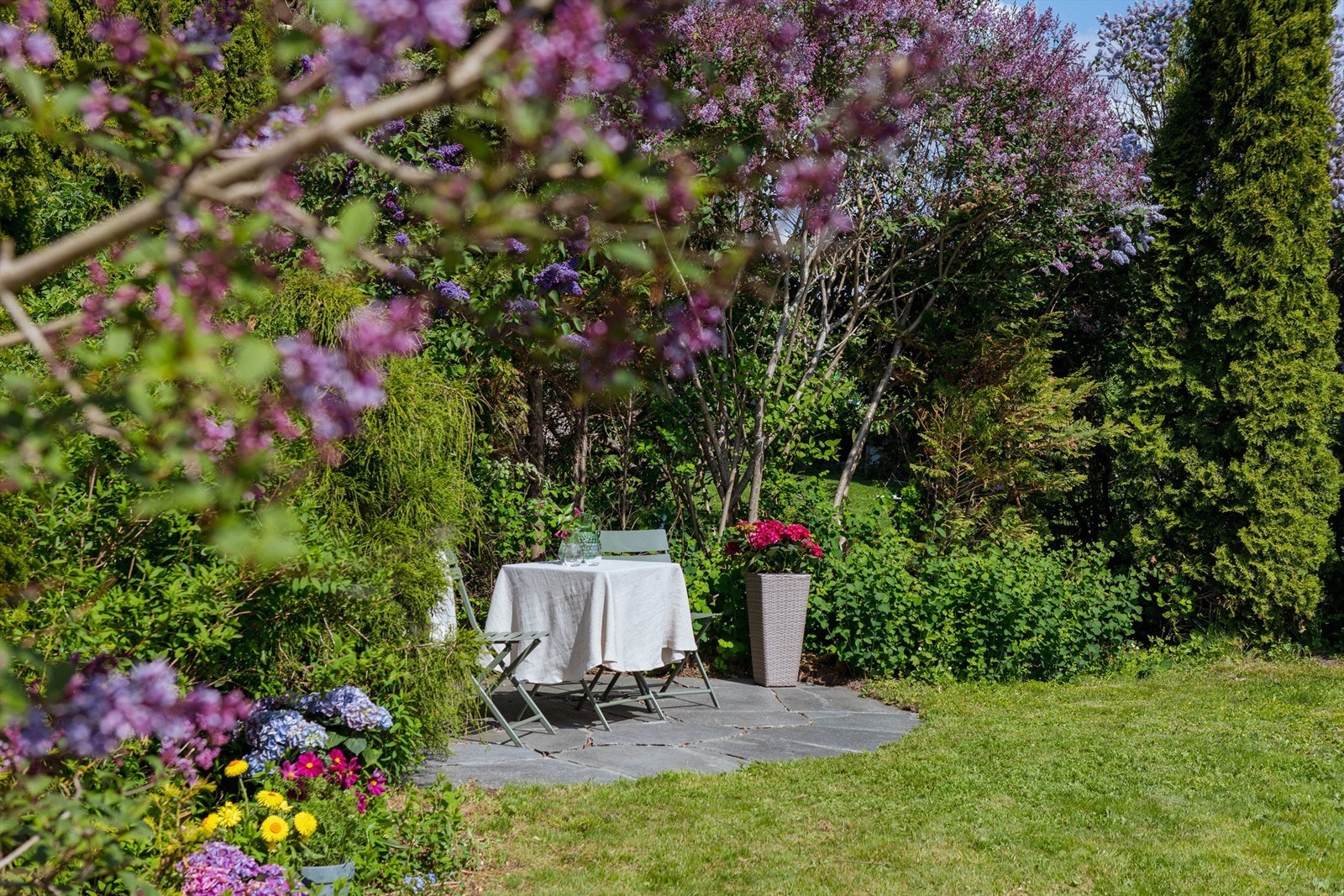 Den frodige hagen byr på flere lune uteplasser hvor solen kan nytes gjennom dagen, omgitt av vakker beplantning og grønne omgivelser. Galleribilde
