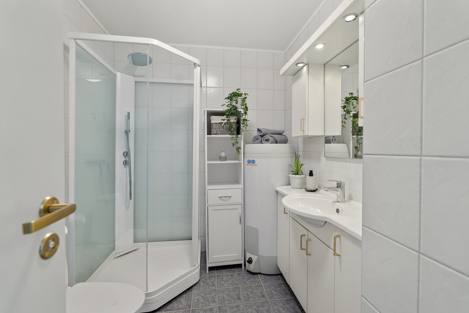Badet er flislagt og har varmekabler i gulvet. Rommet er utstyrt med dusjkabinett fra 2020, toalett og 200 liters varmtvannstank skiftet i 2022. Galleribilde