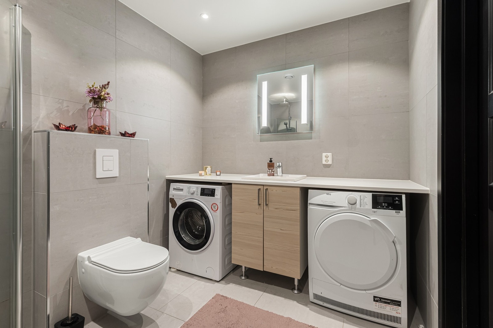 Grå veggfliser kombineres med lysegrå gulvfliser for et stilrent uttrykk(60x60 flis fra Norfloor), og badet har downlights, varmekabler og vegghengt toalett. Galleribilde