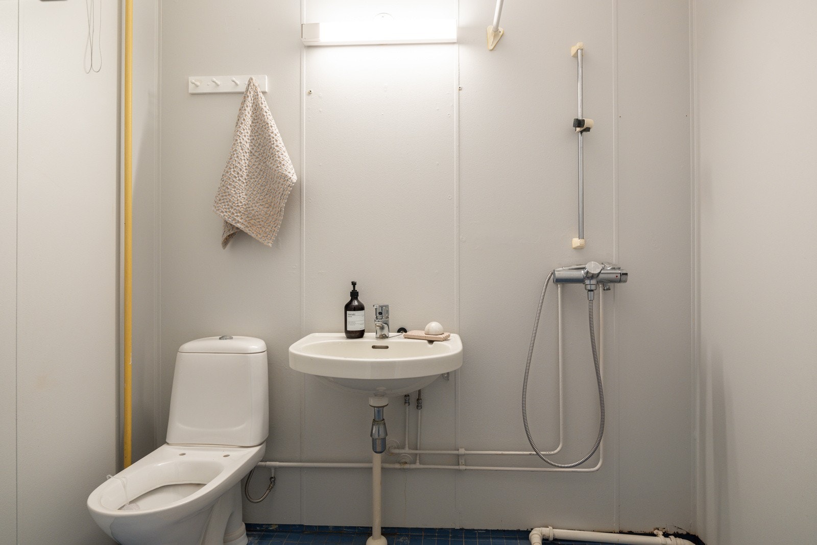 Baderommet er utstyrt med vegghengt servant med belysning over, dusjhjørne med forheng, gulvstående toalett og opplegg for vaskemaskin. Galleribilde