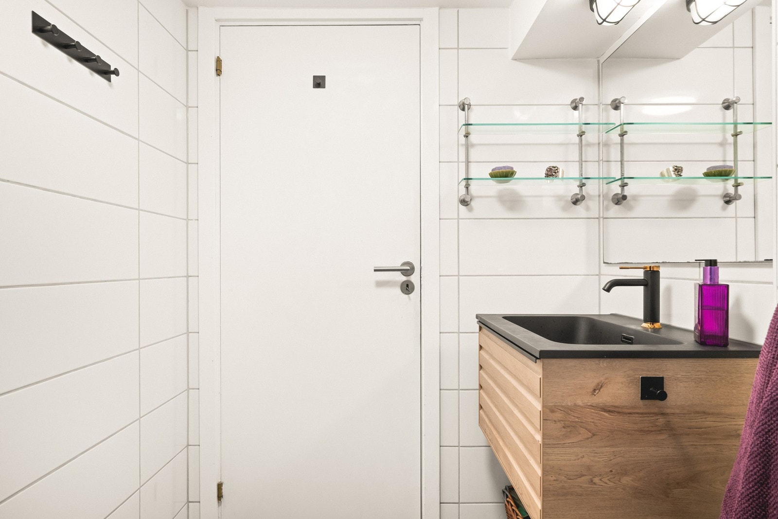 Badet inneholder vegghengt toalett, helstøpt servant, skuffer under servant med profilerte fronter, og dusjdører i klart glass. Galleribilde