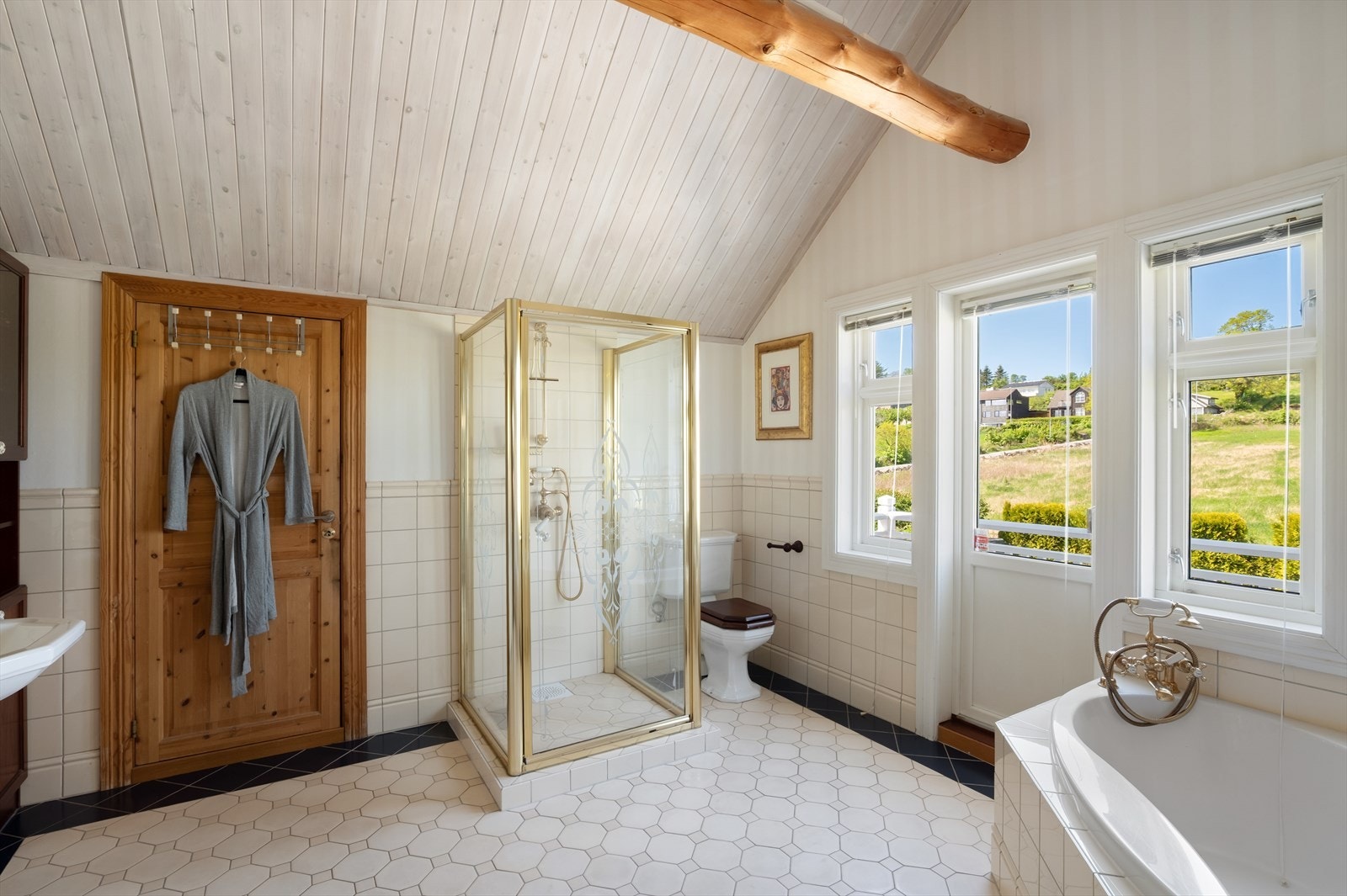 Badet er utstyrt med både badekar og dusj, og har elektriske varmekabler i det flislagte gulvet. Galleribilde