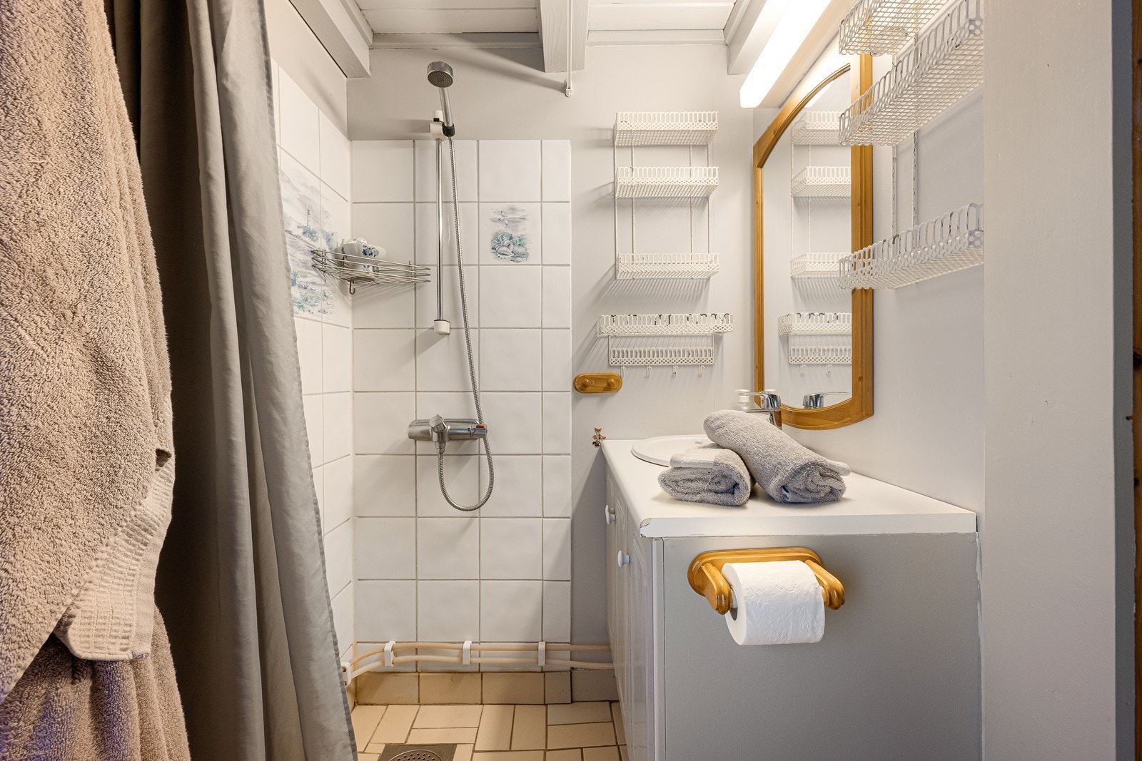Badet har åpent dusjhjørne og innredning med nedfelt servant og i overkant speil med belysning. Galleribilde