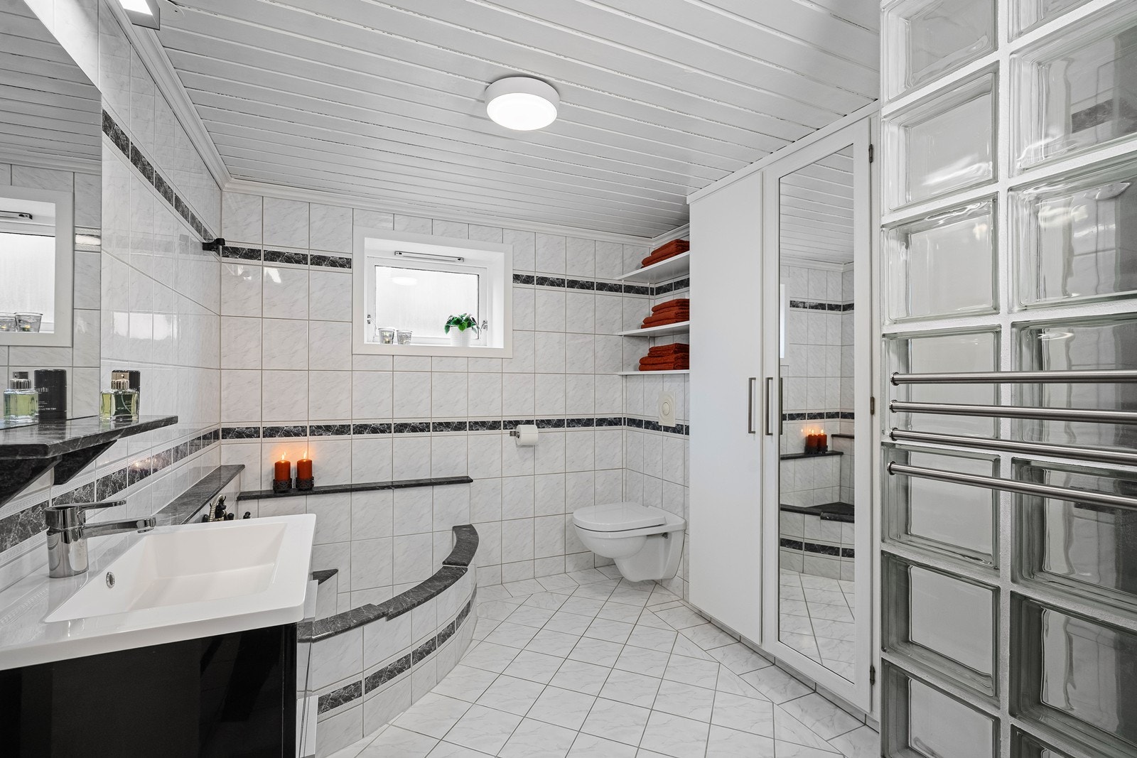 Badet i underetasjen er flislagt og fremstår som romslig og praktisk, med dusjhjørne, servant med innredning og toalett. Galleribilde